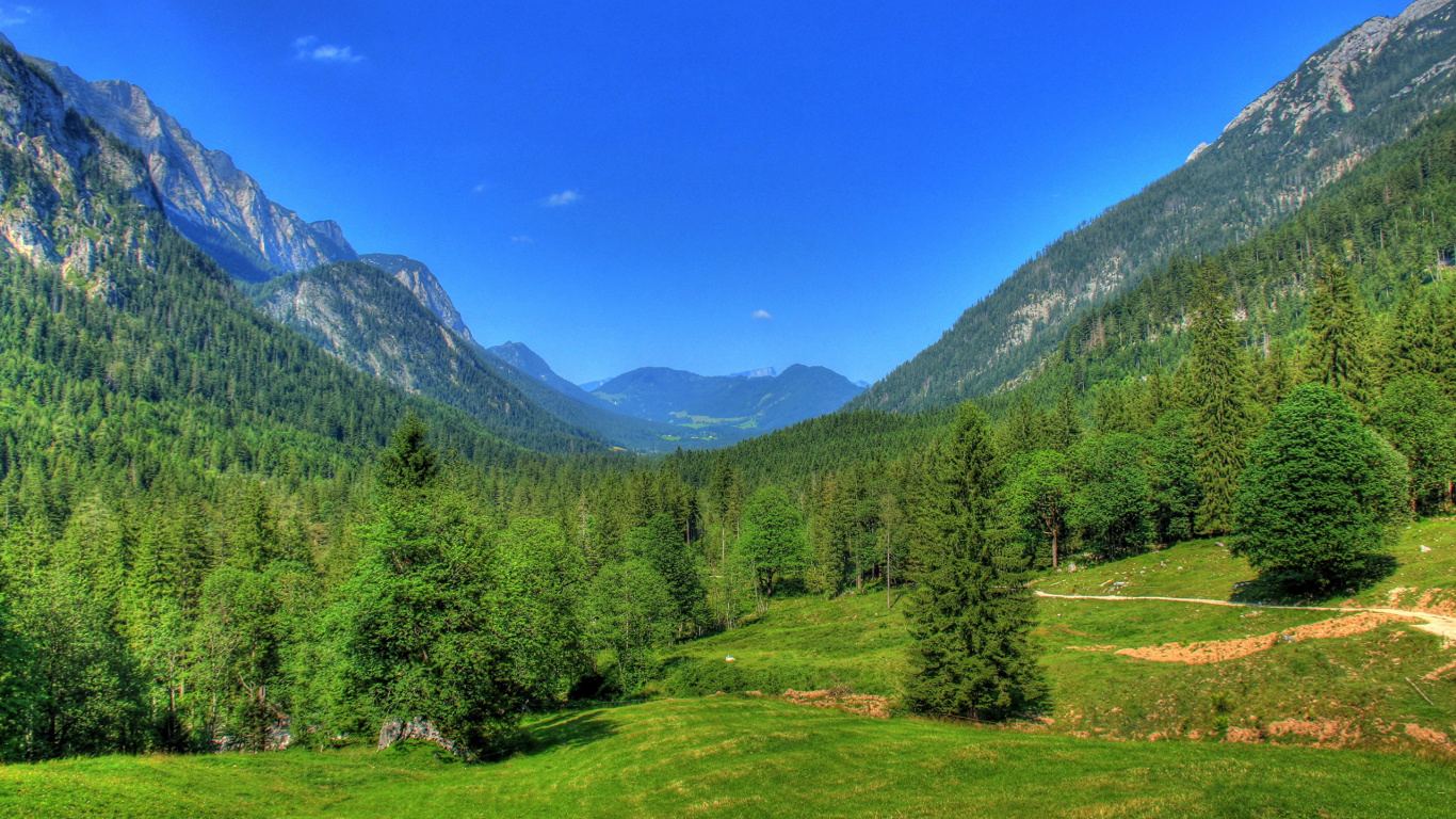 Green Trees on Green Grass Field Near Mountain Under Blue Sky During Daytime. Wallpaper in 1366x768 Resolution