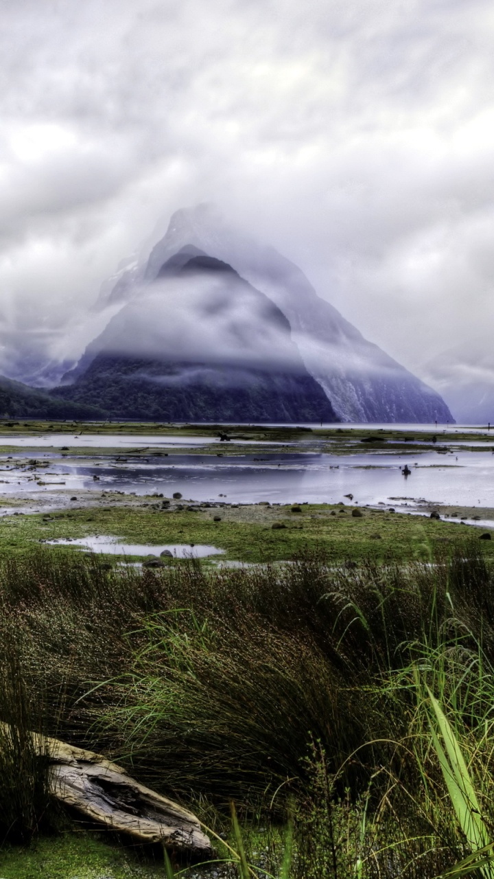 Green Grass Field Near Body of Water and Mountain Under White Clouds During Daytime. Wallpaper in 720x1280 Resolution