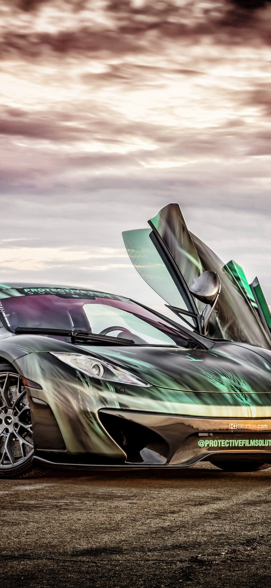 Porsche 911 Verte Sur Champ Brun Sous Ciel Nuageux. Wallpaper in 1125x2436 Resolution