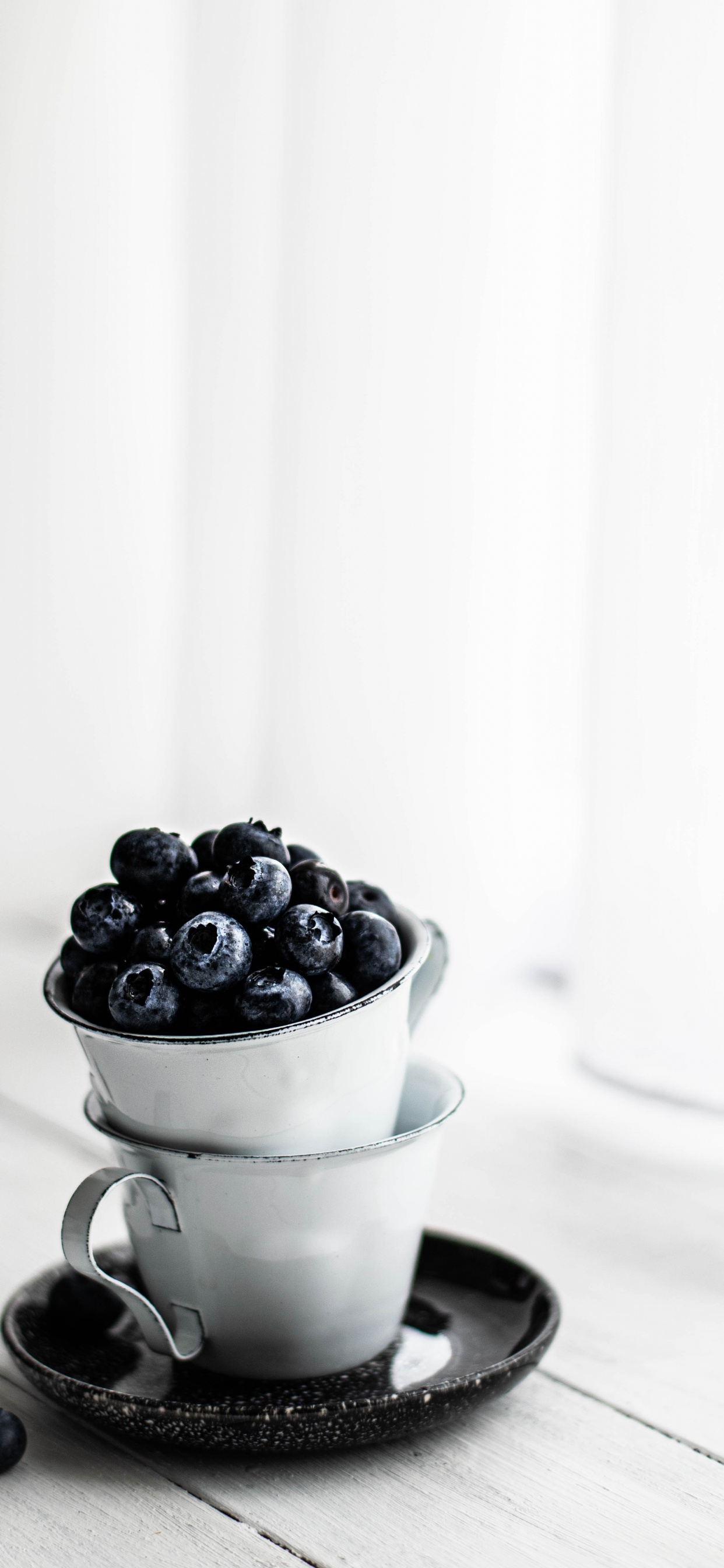 Schwarze Beeren in Weißer Keramiktasse. Wallpaper in 1242x2688 Resolution