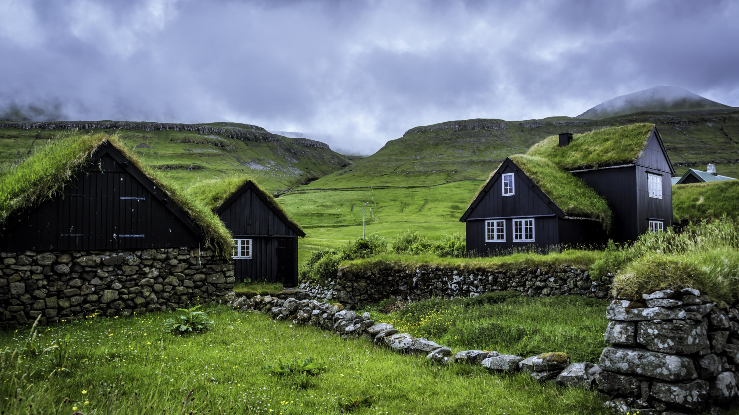 Brown Wooden House on Green Grass Field Near Mountain Under White Clouds During Daytime. Wallpaper in 2560x1440 Resolution