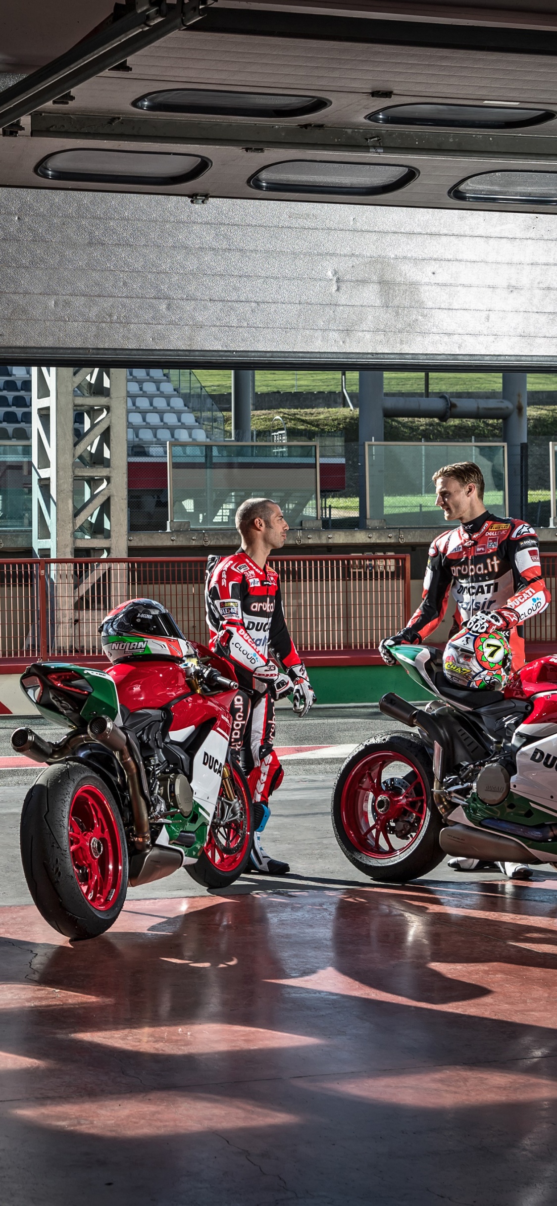 Man in Red and Black Motorcycle Suit Riding on Red Motorcycle. Wallpaper in 1125x2436 Resolution
