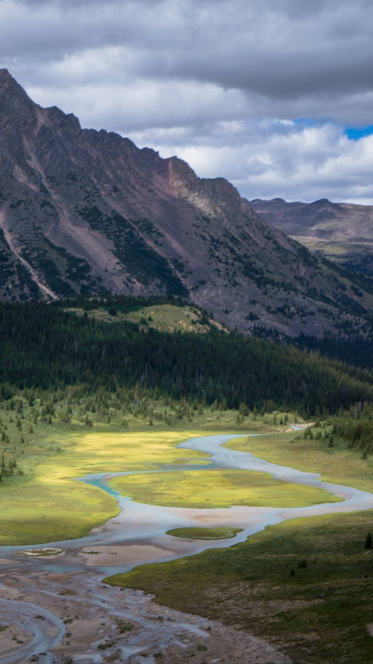 Green Grass Field Near Mountain Under Cloudy Sky During Daytime. Wallpaper in 1440x2560 Resolution