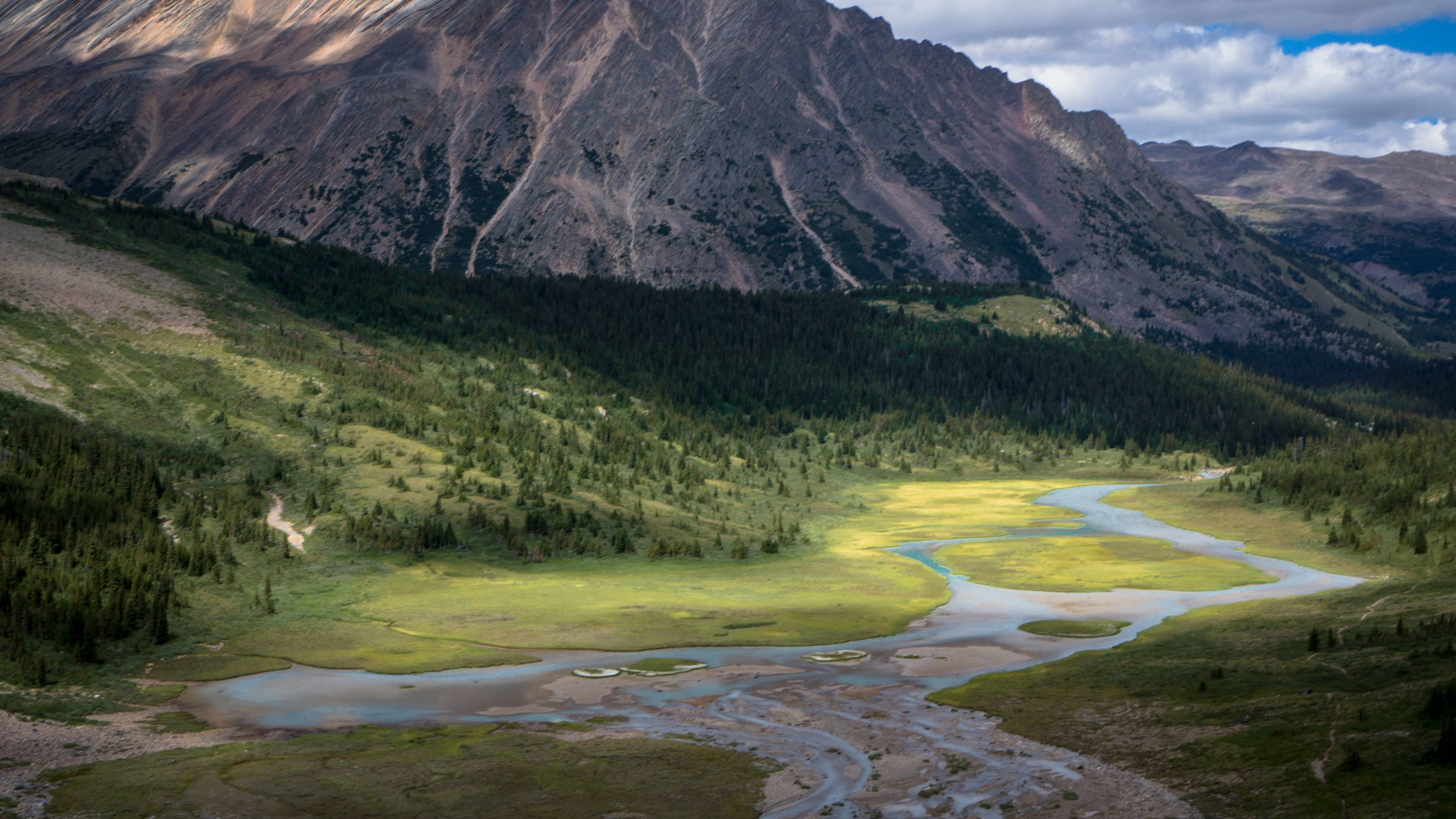 Green Grass Field Near Mountain Under Cloudy Sky During Daytime. Wallpaper in 3840x2160 Resolution