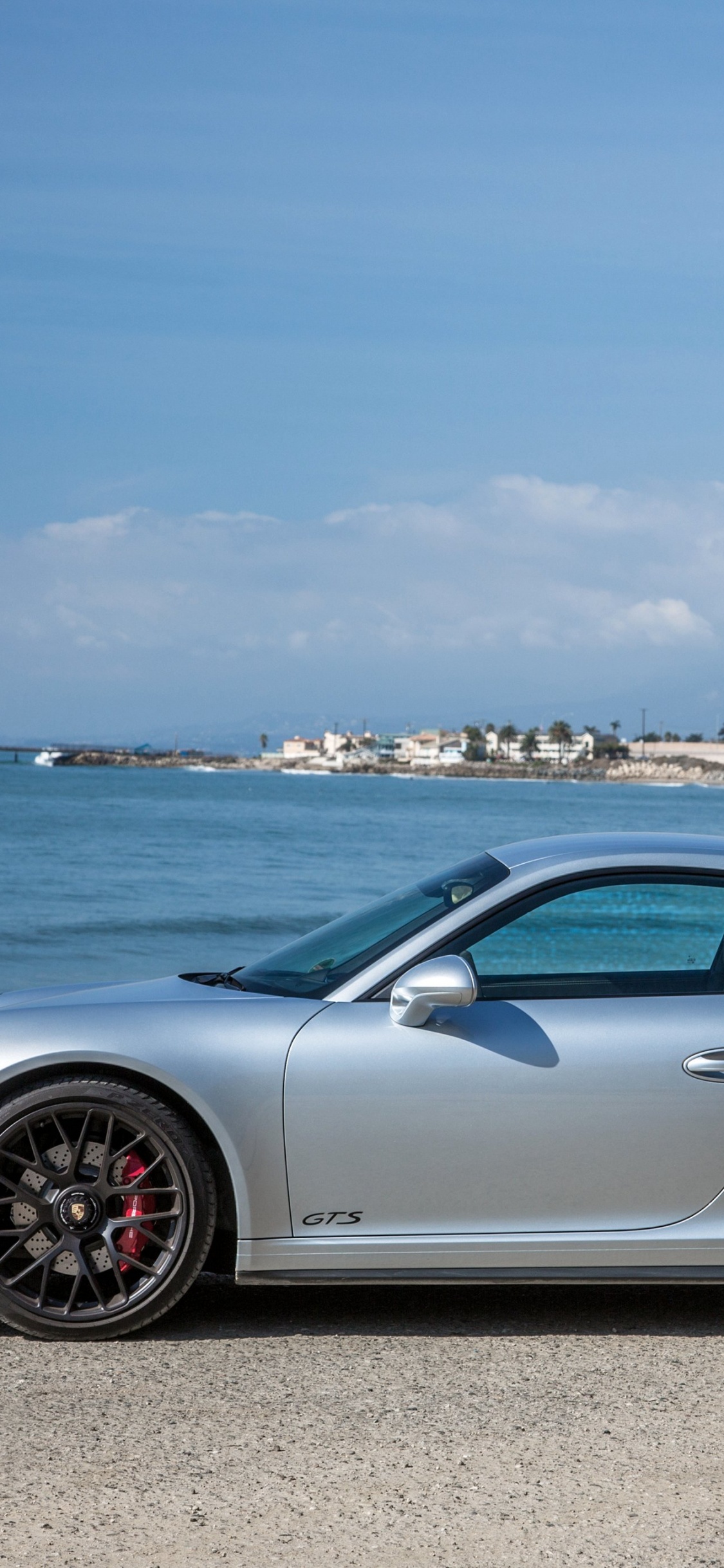Silver Porsche 911 Estacionado en la Orilla Del Mar Durante el Día. Wallpaper in 1125x2436 Resolution