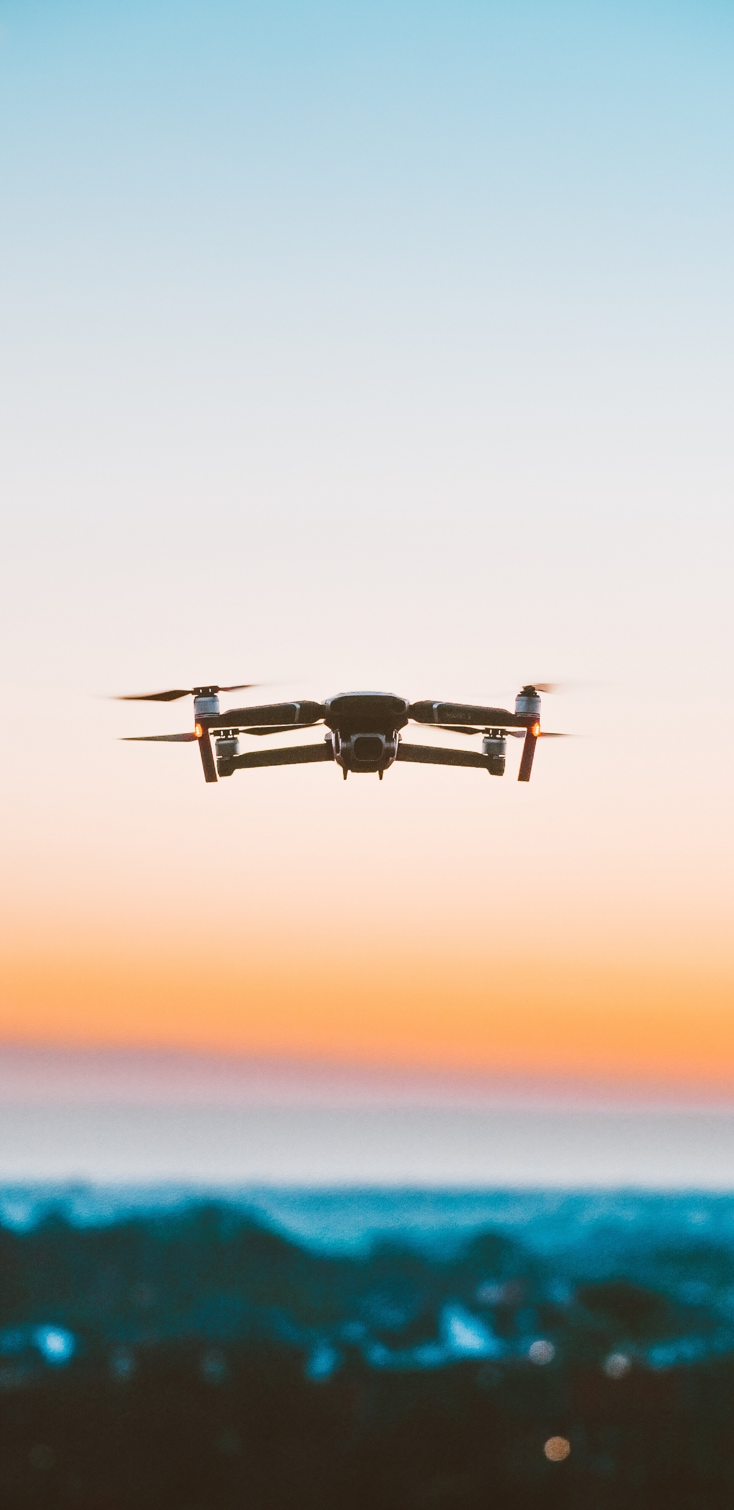 Schwarze Drohne, Die Bei Sonnenuntergang Über Das Meer Fliegt. Wallpaper in 1440x2960 Resolution