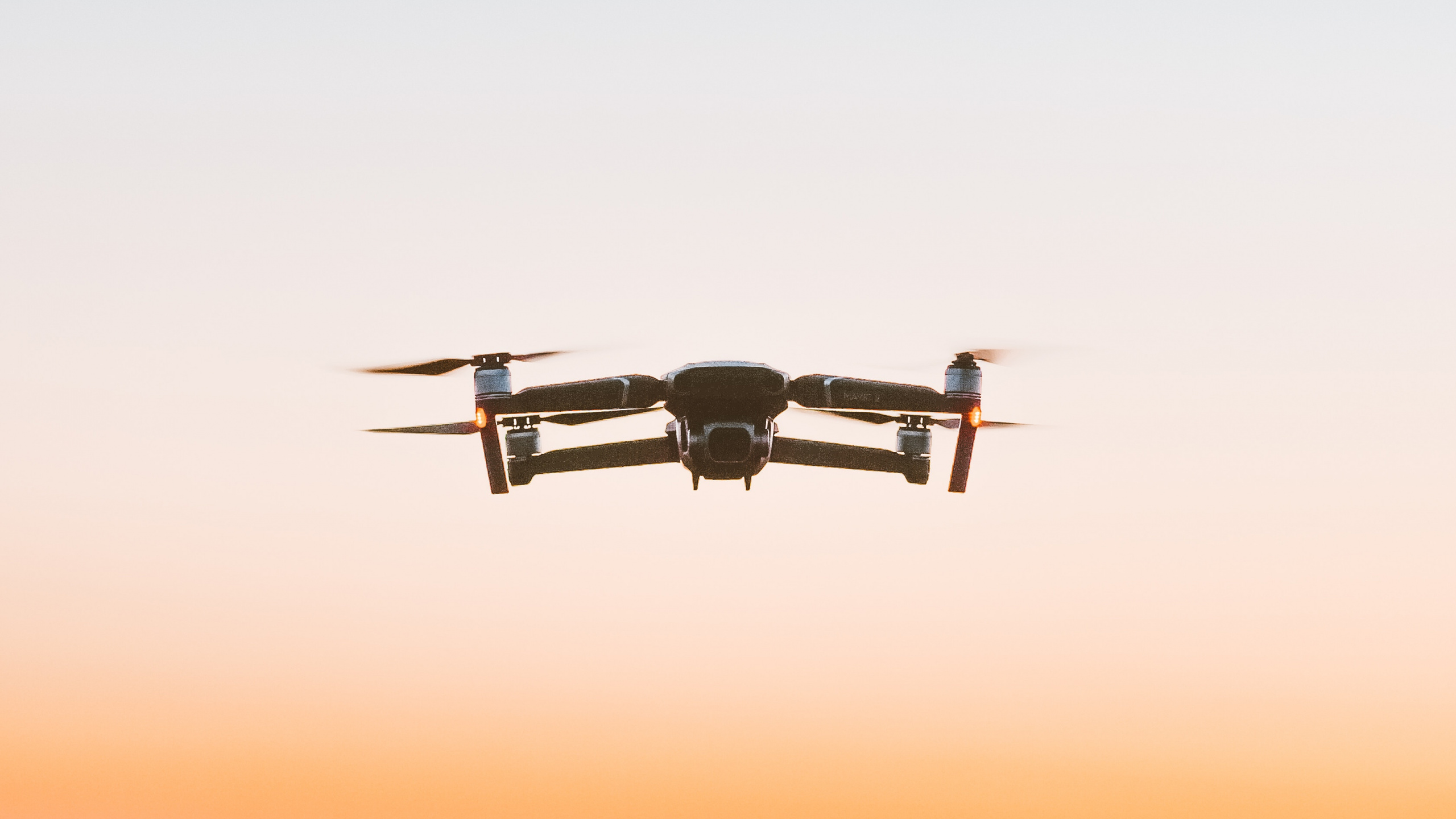 Schwarze Drohne, Die Bei Sonnenuntergang Über Das Meer Fliegt. Wallpaper in 2560x1440 Resolution