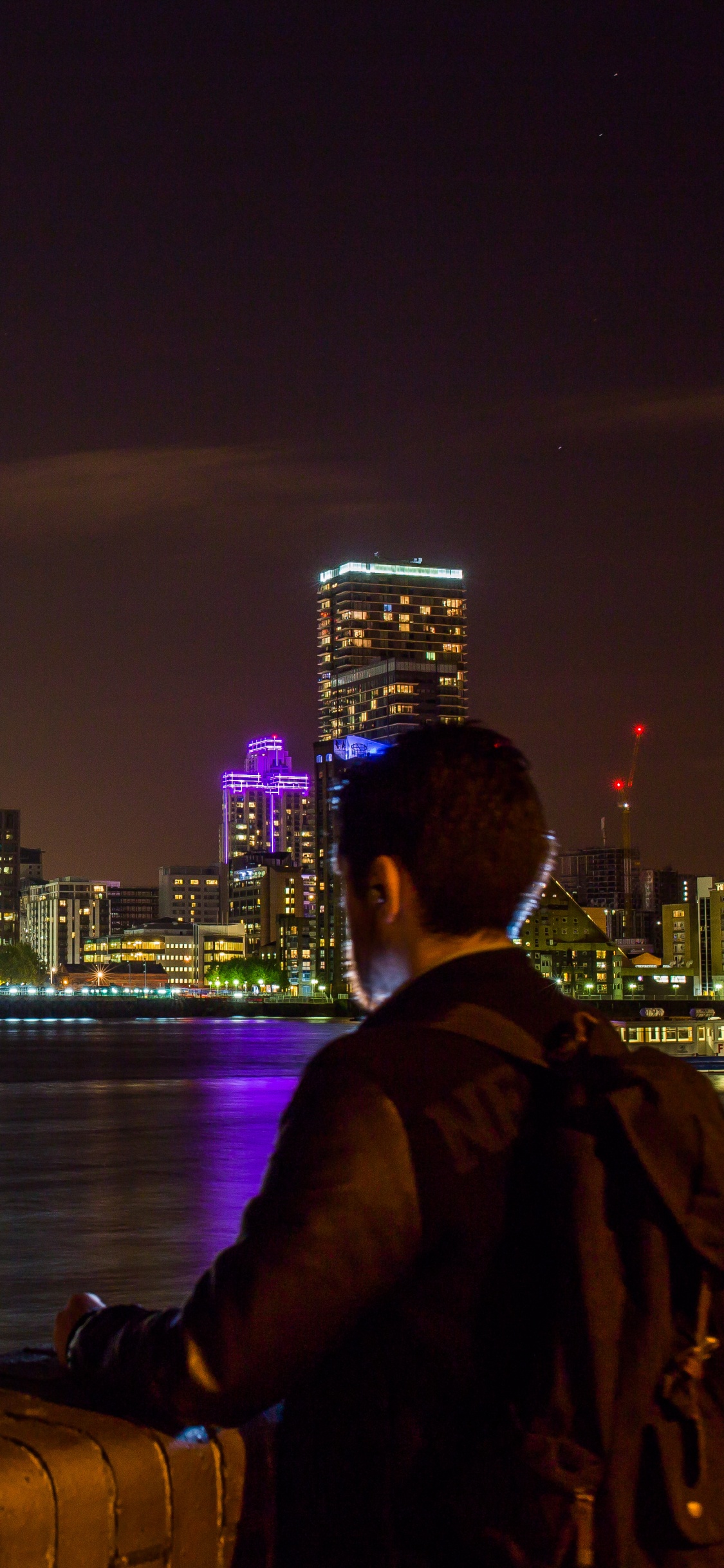 Man in Black Jacket Sitting on Brown Wooden Dock During Night Time. Wallpaper in 1125x2436 Resolution