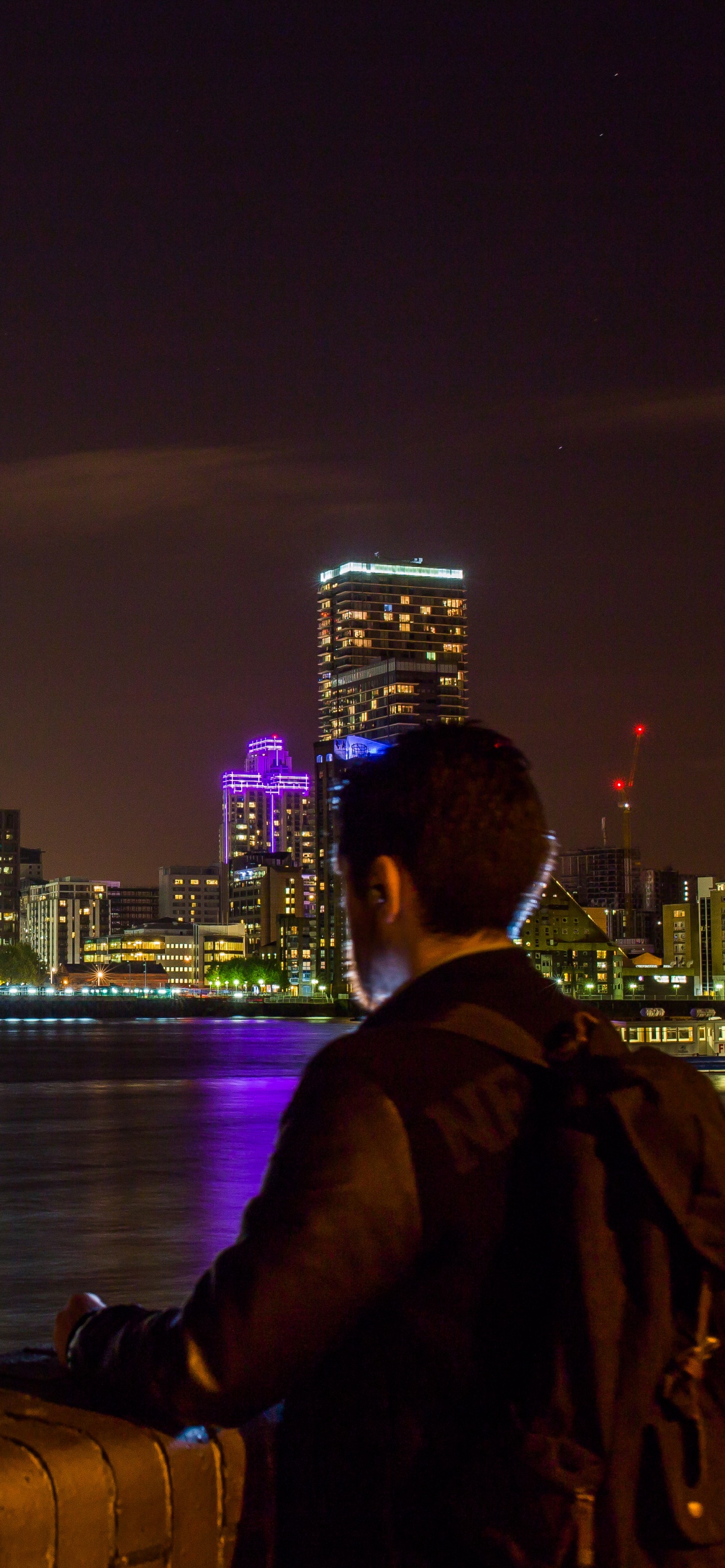 Man in Black Jacket Sitting on Brown Wooden Dock During Night Time. Wallpaper in 1242x2688 Resolution