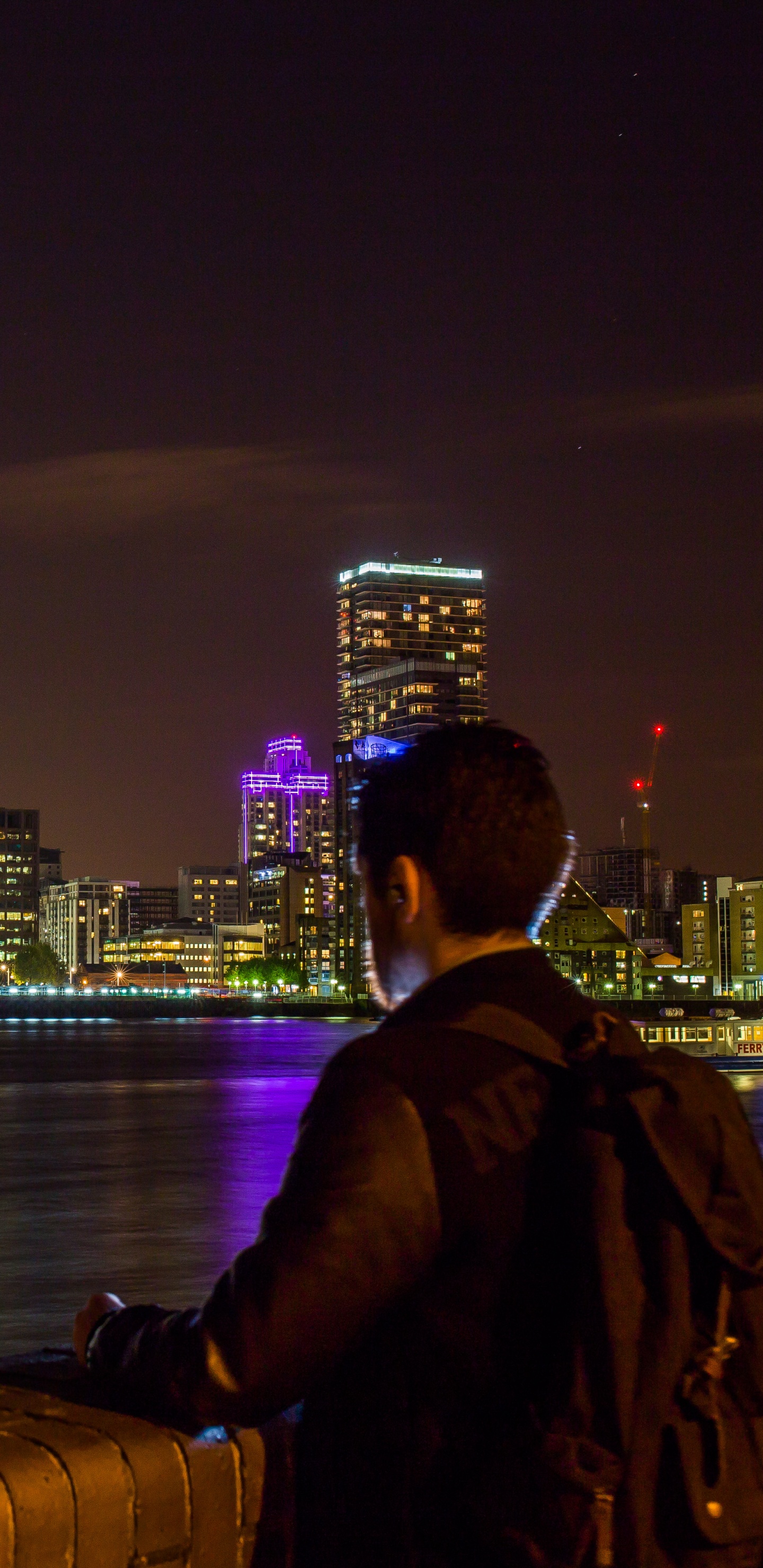 Man in Black Jacket Sitting on Brown Wooden Dock During Night Time. Wallpaper in 1440x2960 Resolution