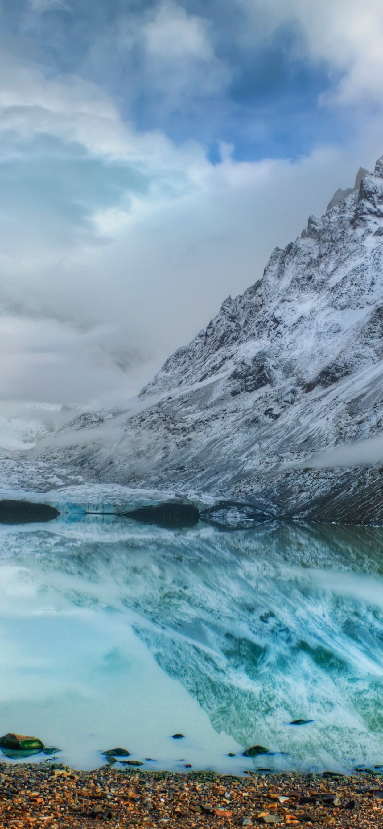 Snow Covered Mountain Near Body of Water Under Cloudy Sky During Daytime. Wallpaper in 1242x2688 Resolution
