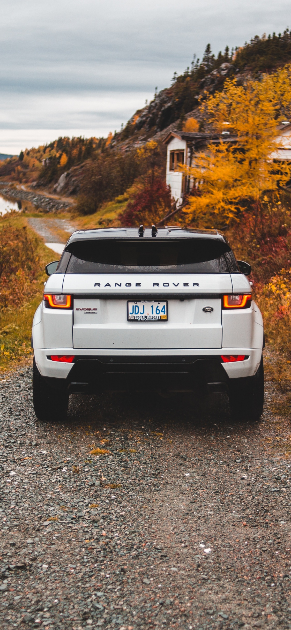 White Nissan Suv on Gray Dirt Road During Daytime. Wallpaper in 1125x2436 Resolution