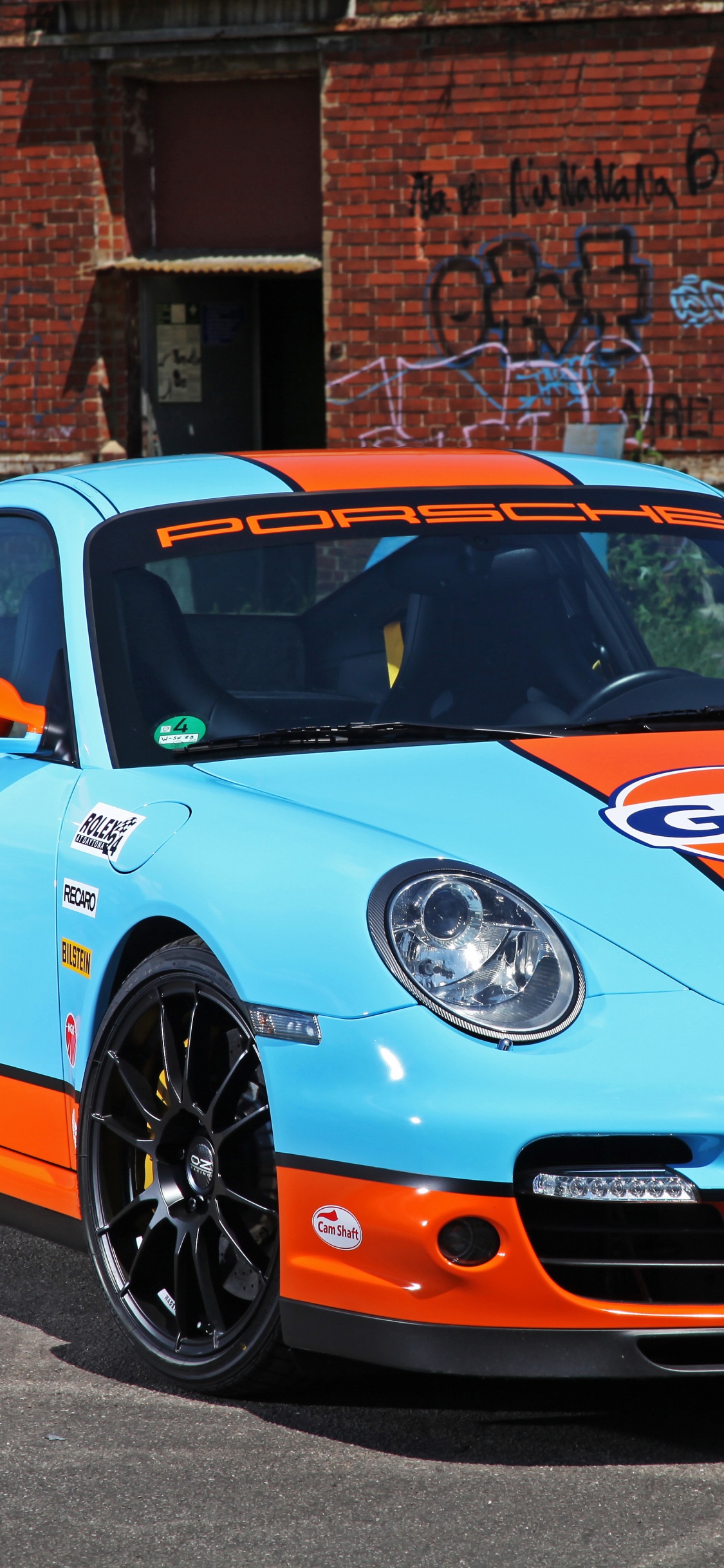 Blau-weißer Porsche 911 Geparkt in Der Nähe Eines Braunen Backsteingebäudes Tagsüber. Wallpaper in 1125x2436 Resolution