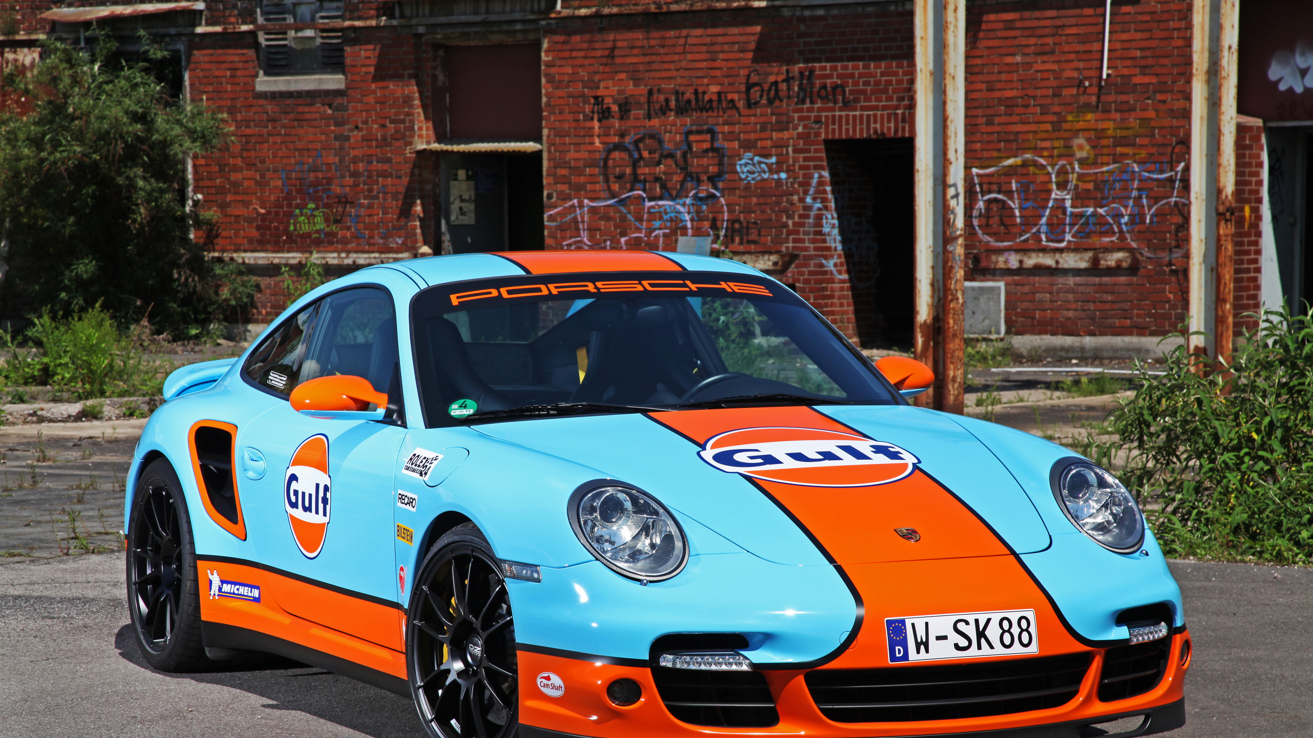 Blau-weißer Porsche 911 Geparkt in Der Nähe Eines Braunen Backsteingebäudes Tagsüber. Wallpaper in 2560x1440 Resolution