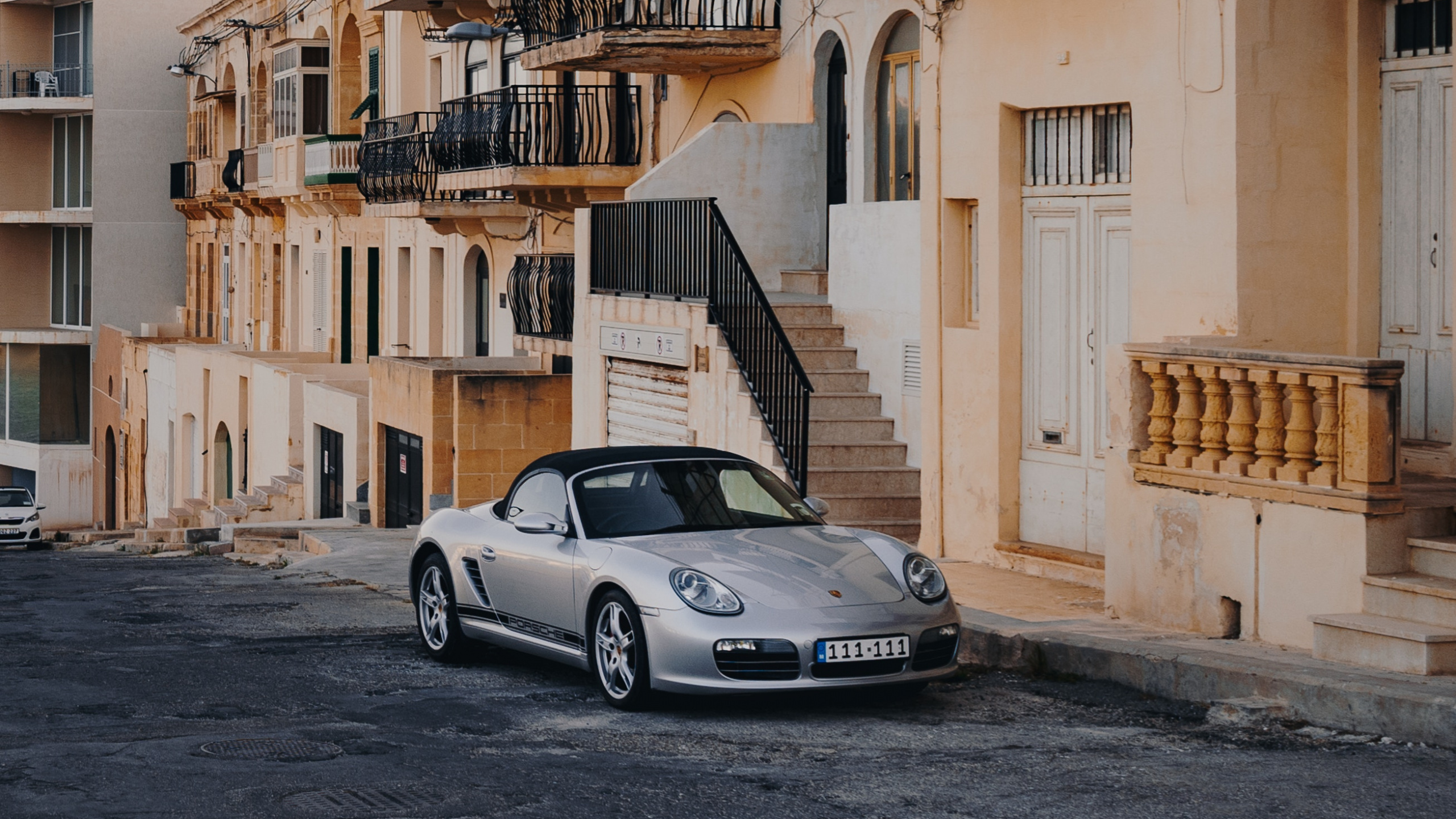 Porsche 911 Blanco Estacionado Junto al Edificio de Hormigón Amarillo Durante el Día. Wallpaper in 2560x1440 Resolution