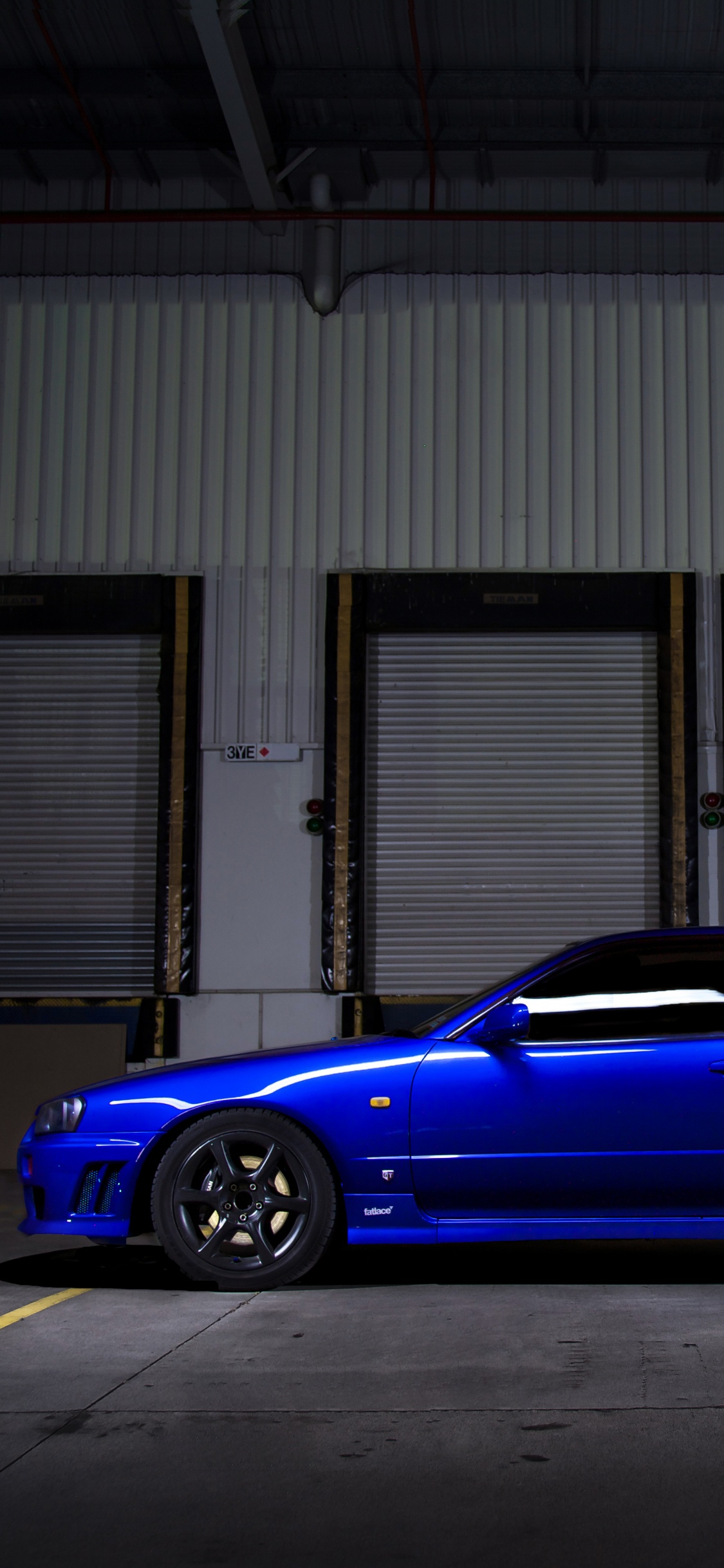 Sedán Azul Estacionado Frente al Edificio. Wallpaper in 1125x2436 Resolution