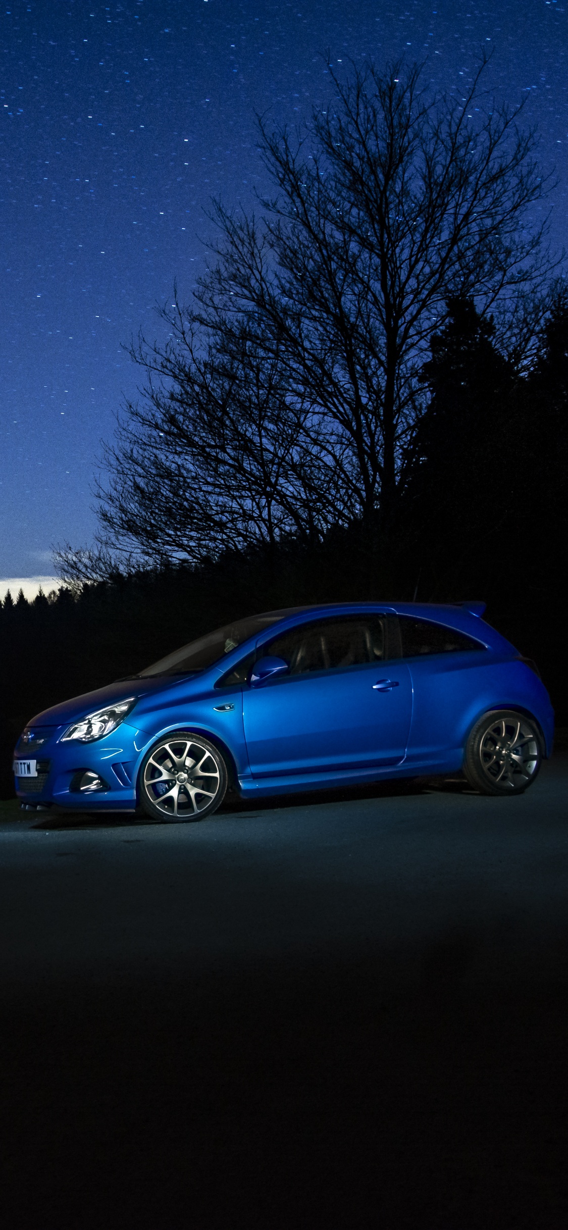 Berline Bleue Garée Près D'un Arbre Pendant la Nuit. Wallpaper in 1125x2436 Resolution