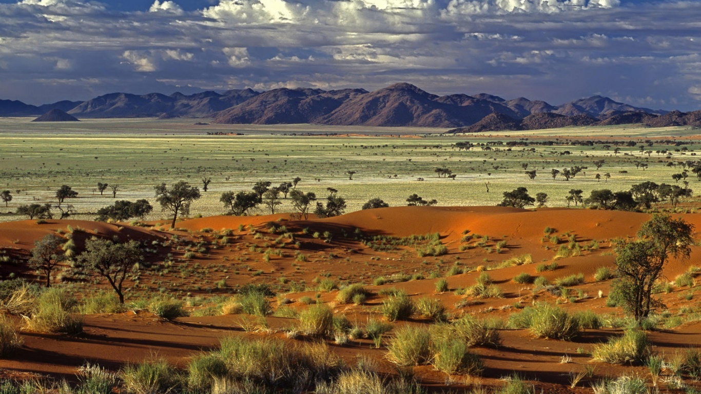 Brown and Green Grass Field Near Mountains Under Blue Sky During Daytime. Wallpaper in 1366x768 Resolution