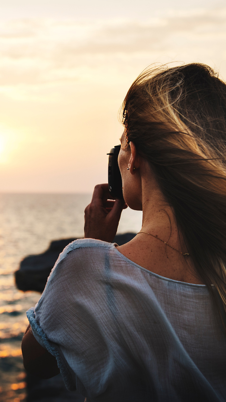Woman in White Shirt Taking Photo of Sea During Daytime. Wallpaper in 750x1334 Resolution