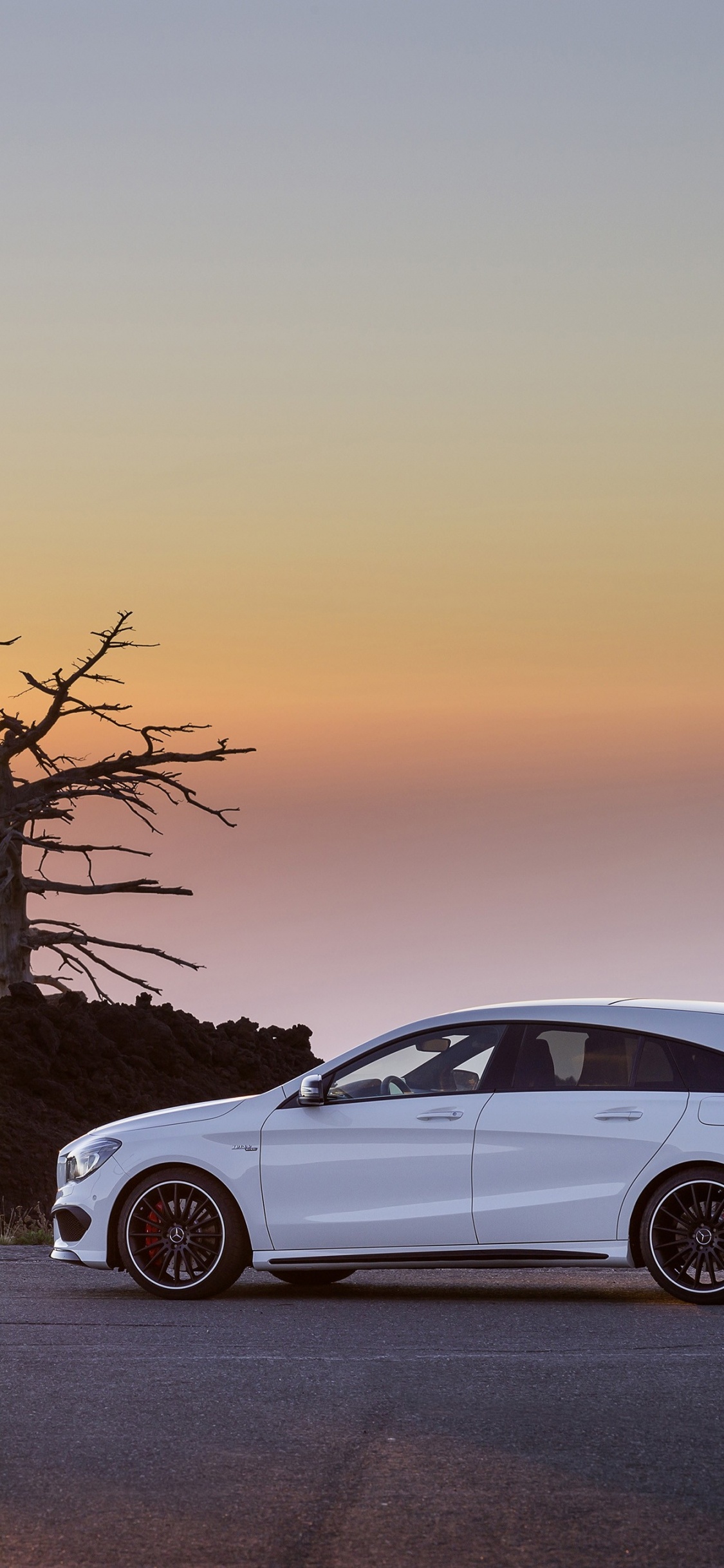 White Sedan on Snow Covered Road During Sunset. Wallpaper in 1125x2436 Resolution