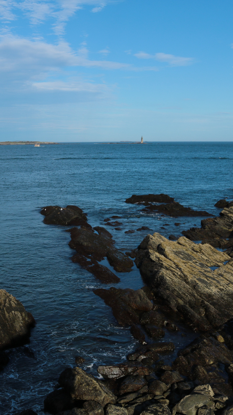 Brown Rocks on Sea Under Blue Sky During Daytime. Wallpaper in 750x1334 Resolution