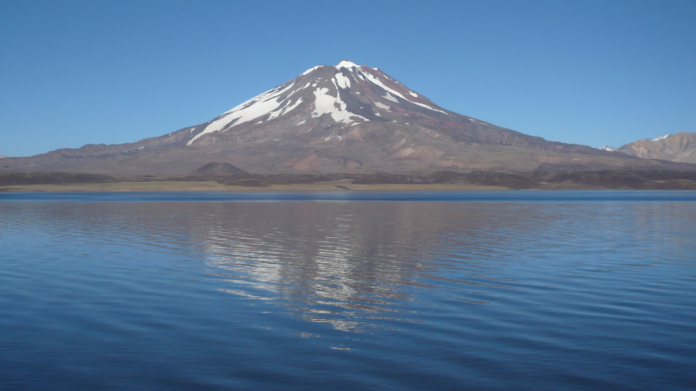 Snow Covered Mountain Near Body of Water During Daytime. Wallpaper in 1366x768 Resolution