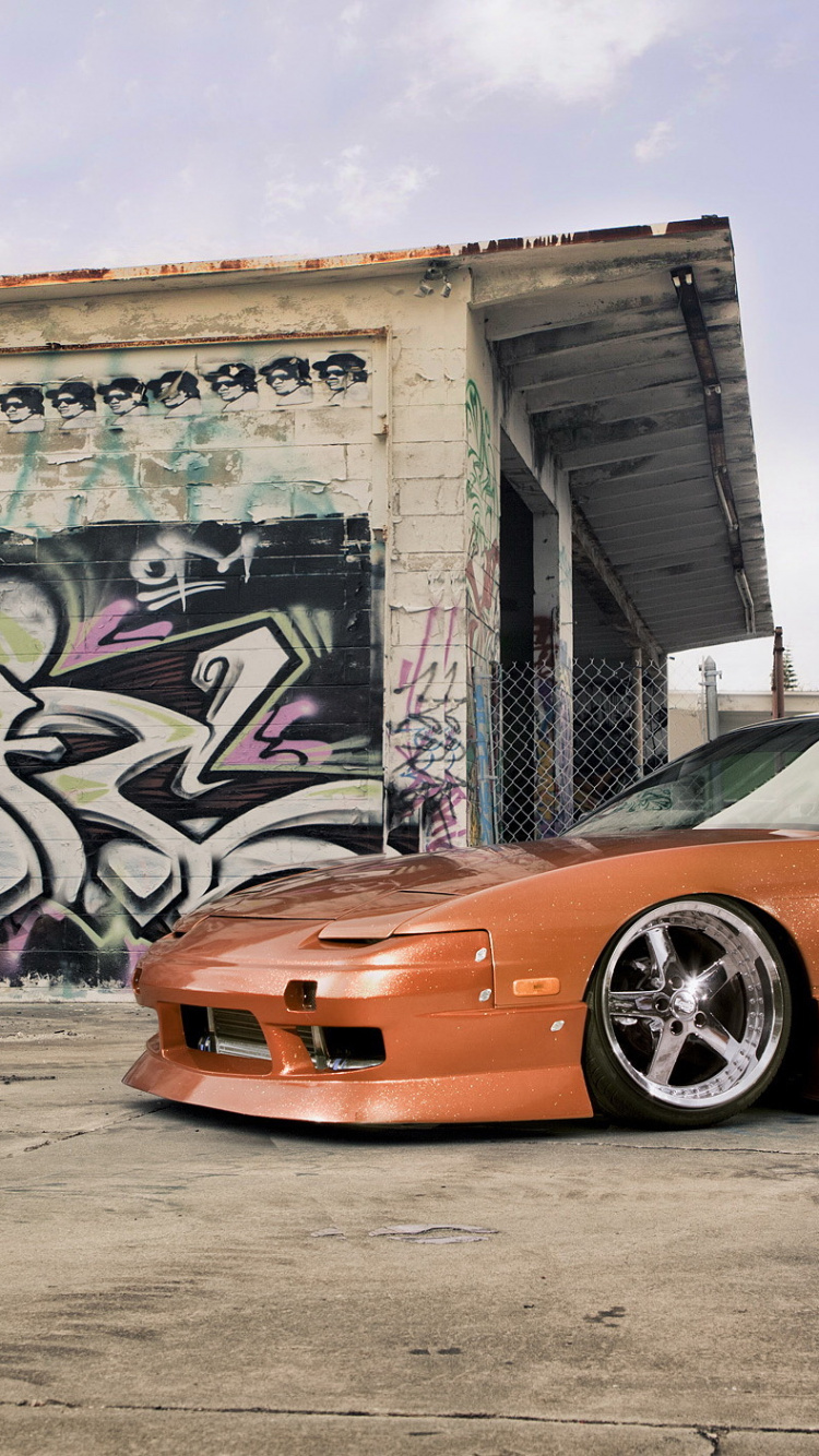 Orange Porsche 911 Geparkt Neben Wand Mit Graffiti. Wallpaper in 750x1334 Resolution