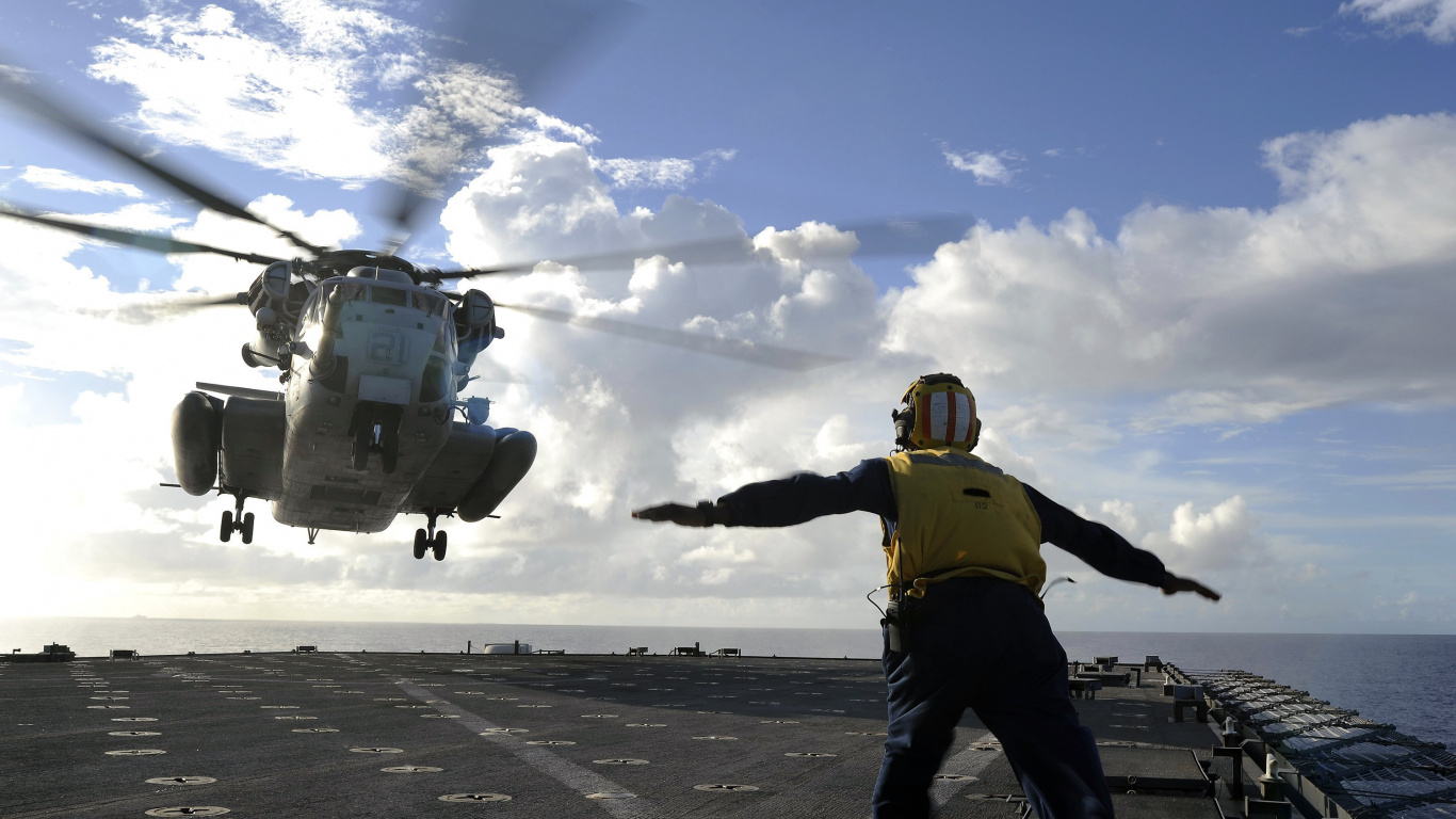 Man in Yellow Jacket and Black Pants Standing on Gray Concrete Floor. Wallpaper in 1366x768 Resolution