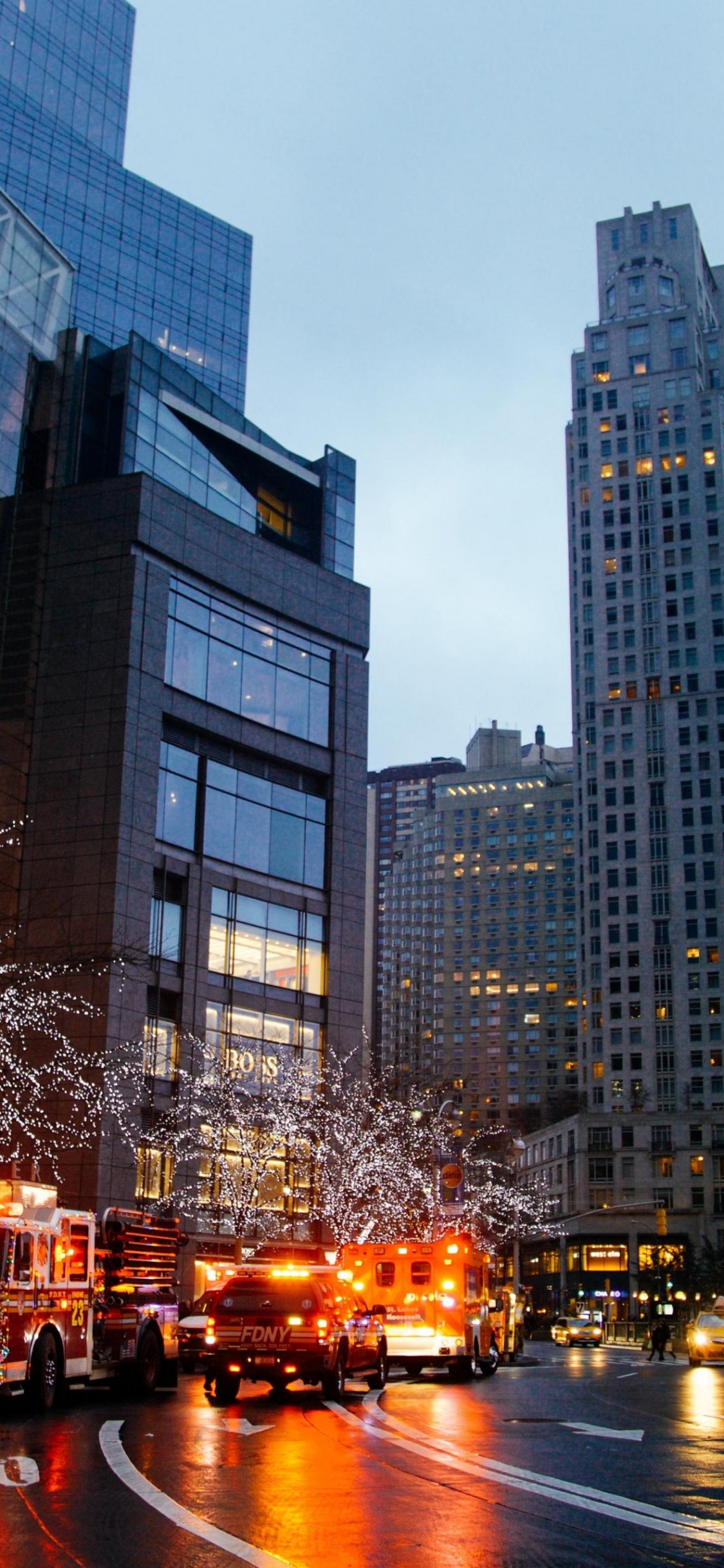 Autos Auf Der Straße in Der Nähe Von Hochhäusern Während Der Nacht. Wallpaper in 1125x2436 Resolution