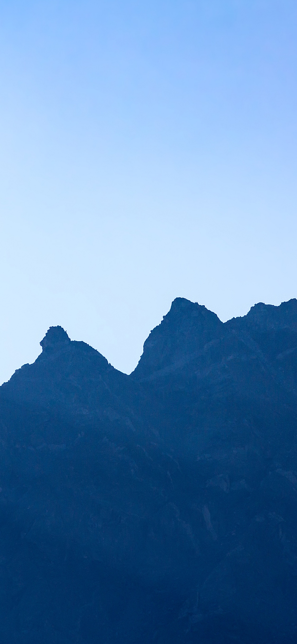 Tagsüber Schwarze Berge Unter Blauem Himmel. Wallpaper in 1125x2436 Resolution