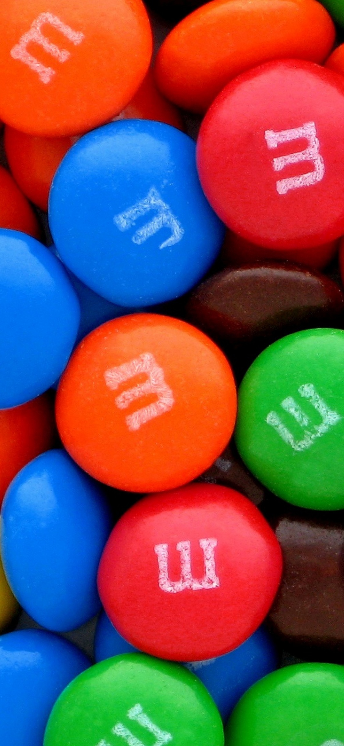 Blue Orange Green and Yellow m ms Chocolate Candies. Wallpaper in 1125x2436 Resolution