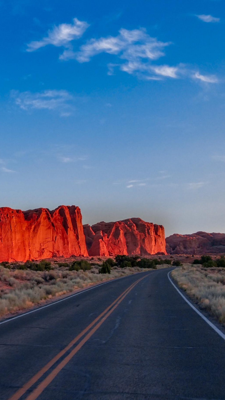 Route Asphaltée Grise Entre Brown Rock Formation Sous Ciel Bleu Pendant la Journée. Wallpaper in 750x1334 Resolution