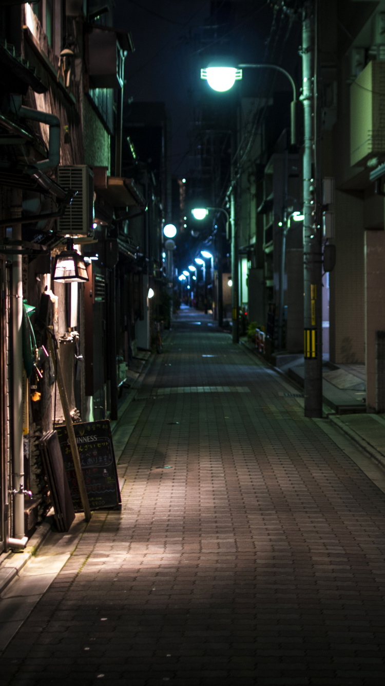Empty Street With Lighted Lamp Posts During Night Time. Wallpaper in 750x1334 Resolution