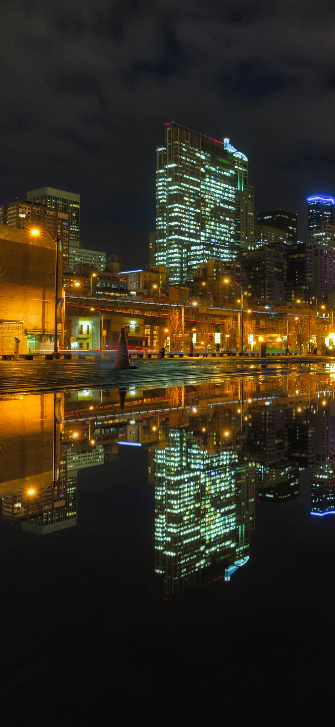 City Skyline Across Body of Water During Night Time. Wallpaper in 1125x2436 Resolution