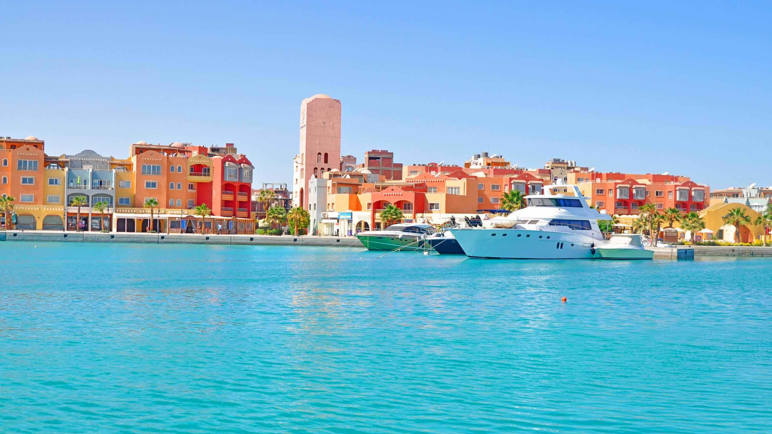 Bateau Blanc Sur la Mer Près Des Bâtiments de la Ville Pendant la Journée. Wallpaper in 2560x1440 Resolution