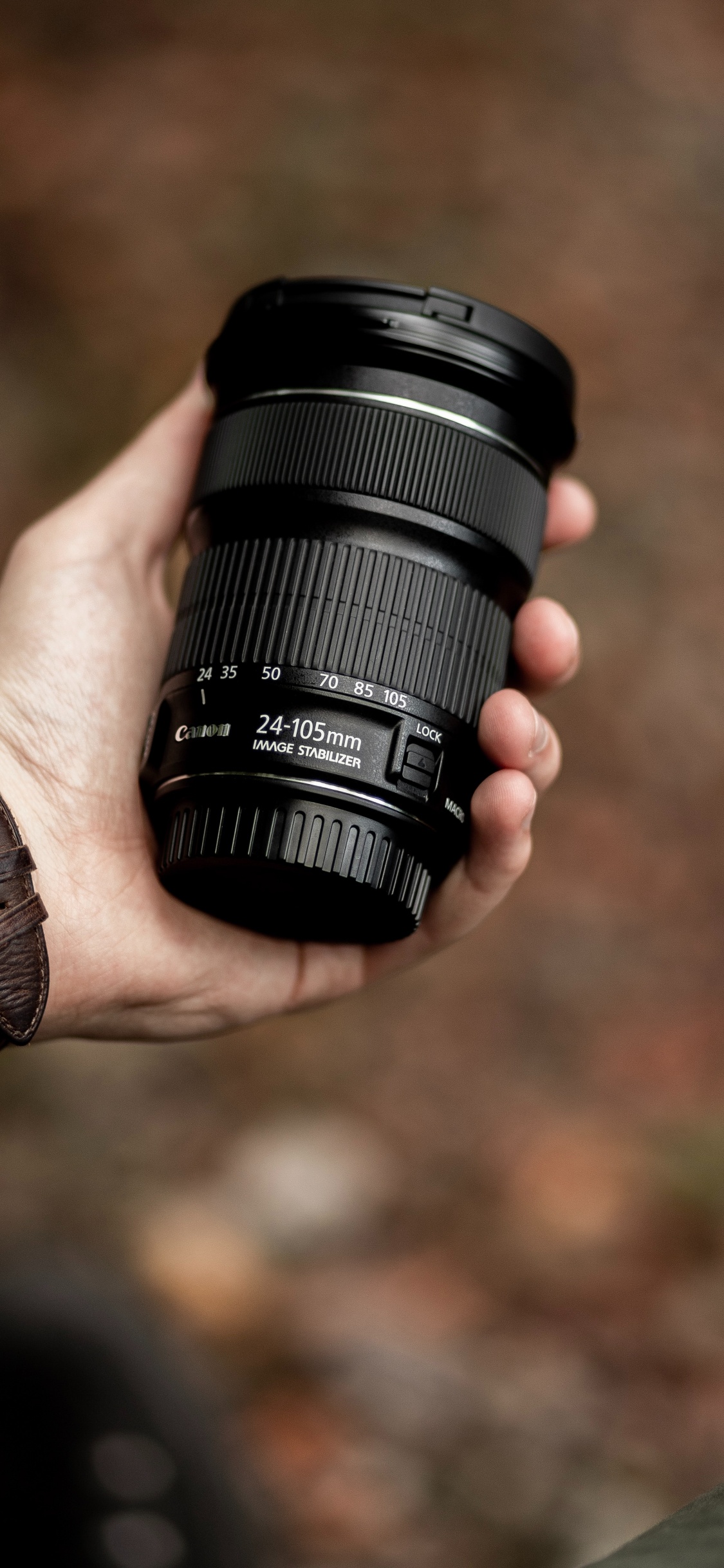 Person Holding Black Camera Lens. Wallpaper in 1125x2436 Resolution