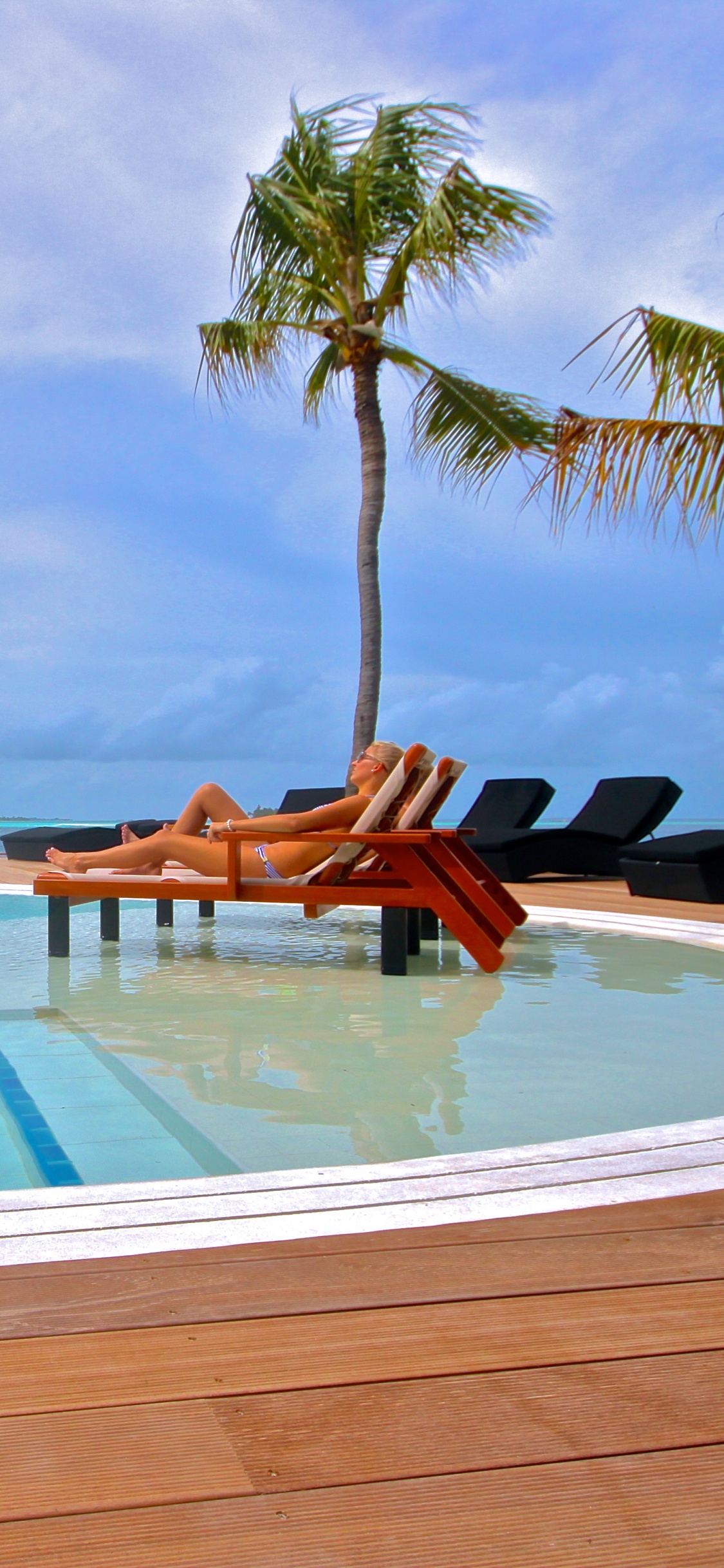 2 Chaises Longues en Bois Marron Sur la Plage de Sable Blanc Pendant la Journée. Wallpaper in 1125x2436 Resolution