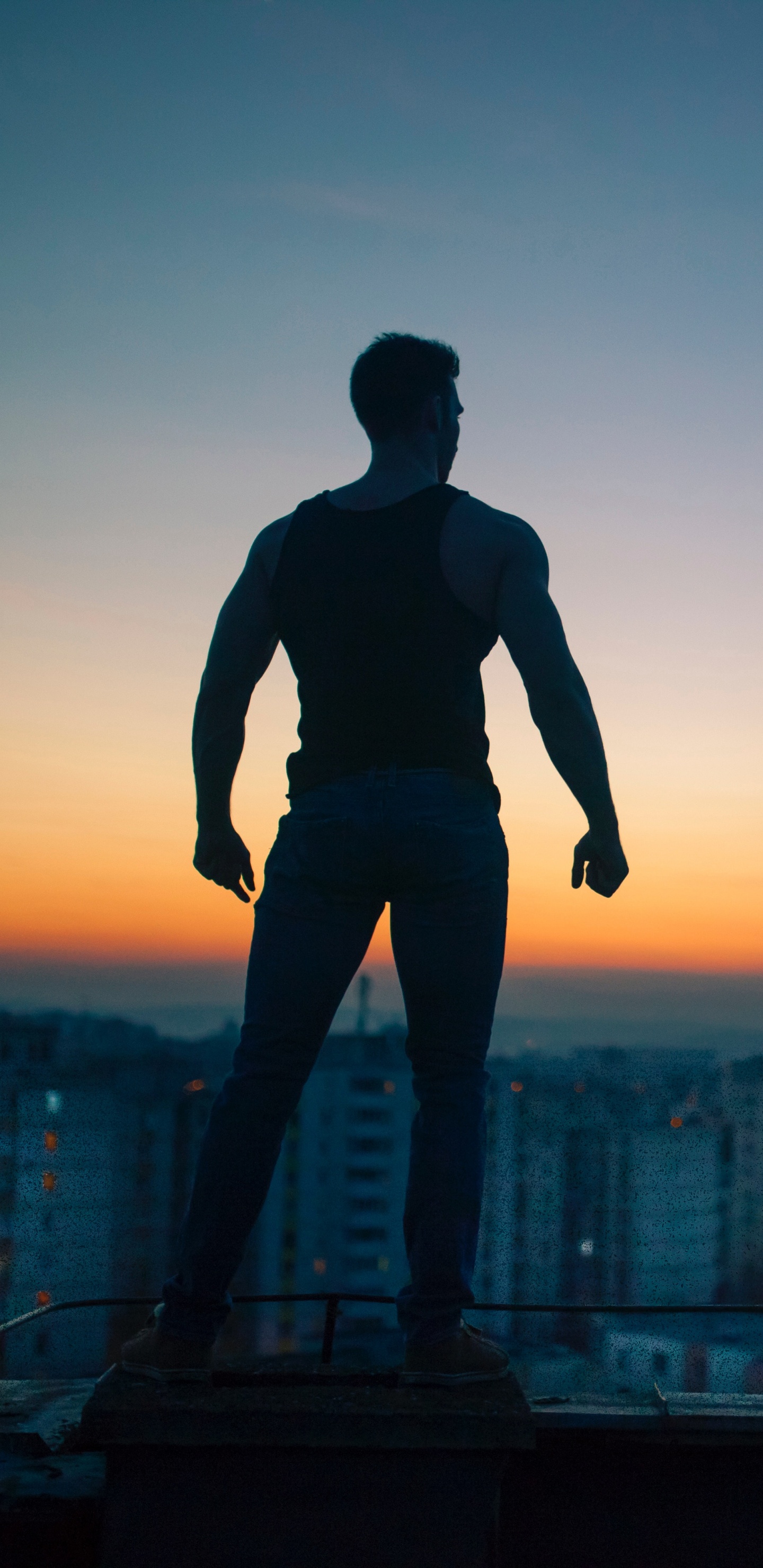 Mann in Schwarzem Hemd Und Hose, Der Während Des Sonnenuntergangs Auf Dem Gebäude Steht. Wallpaper in 1440x2960 Resolution