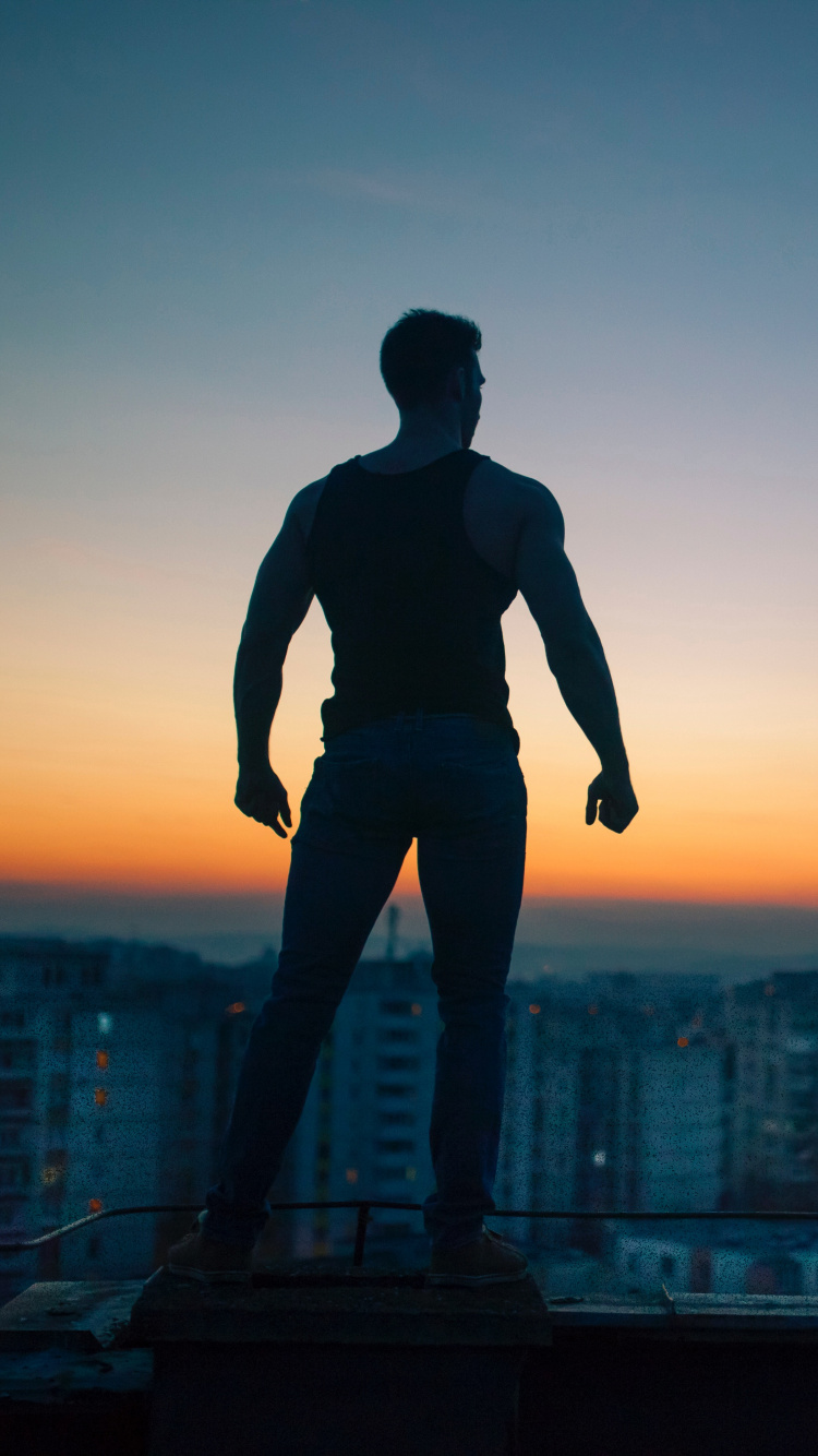 Man in Black Shirt and Pants Standing on Top of Building During Sunset. Wallpaper in 750x1334 Resolution