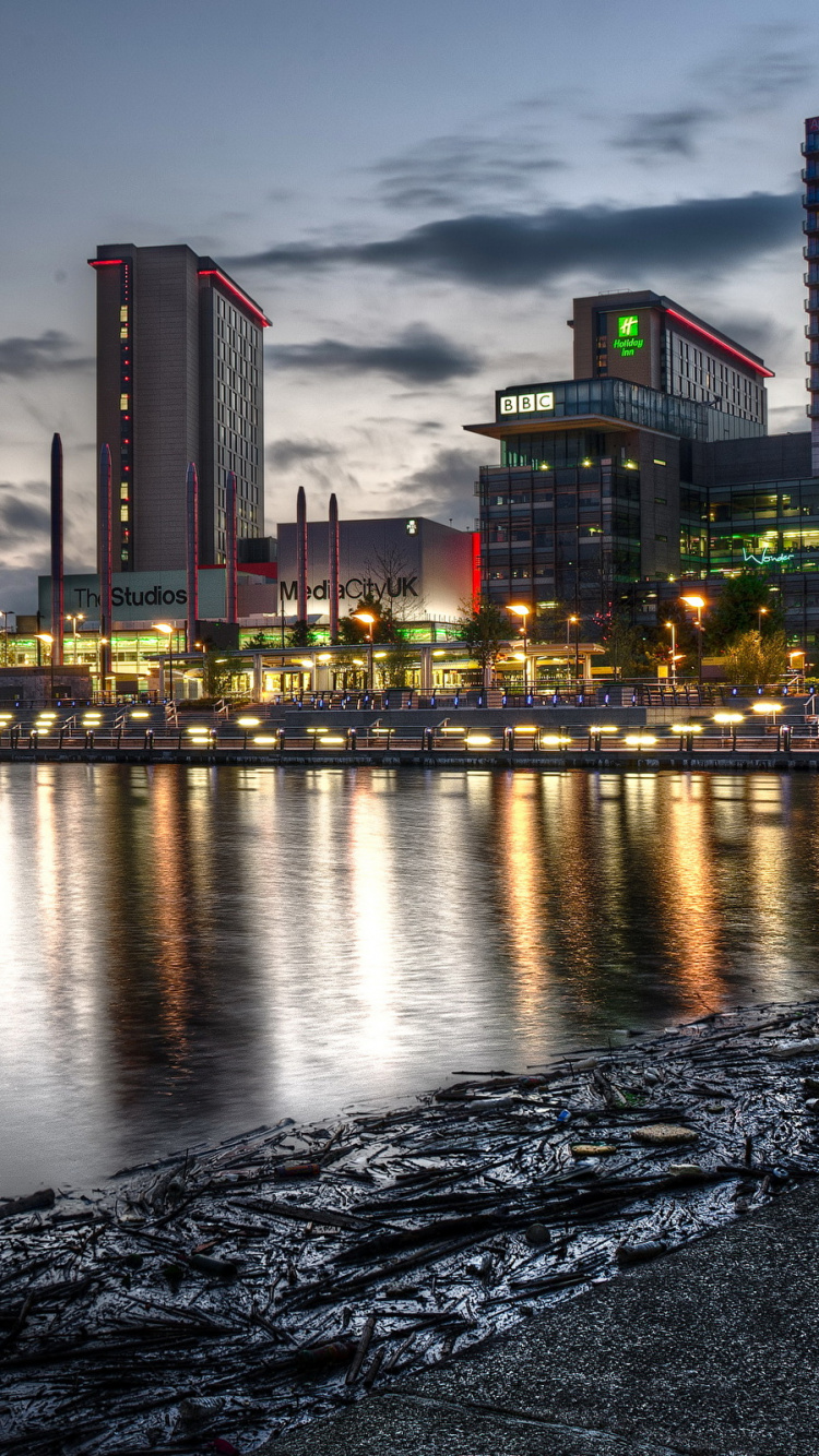Skyline Der Stadt Über Gewässer Während Der Nacht. Wallpaper in 750x1334 Resolution