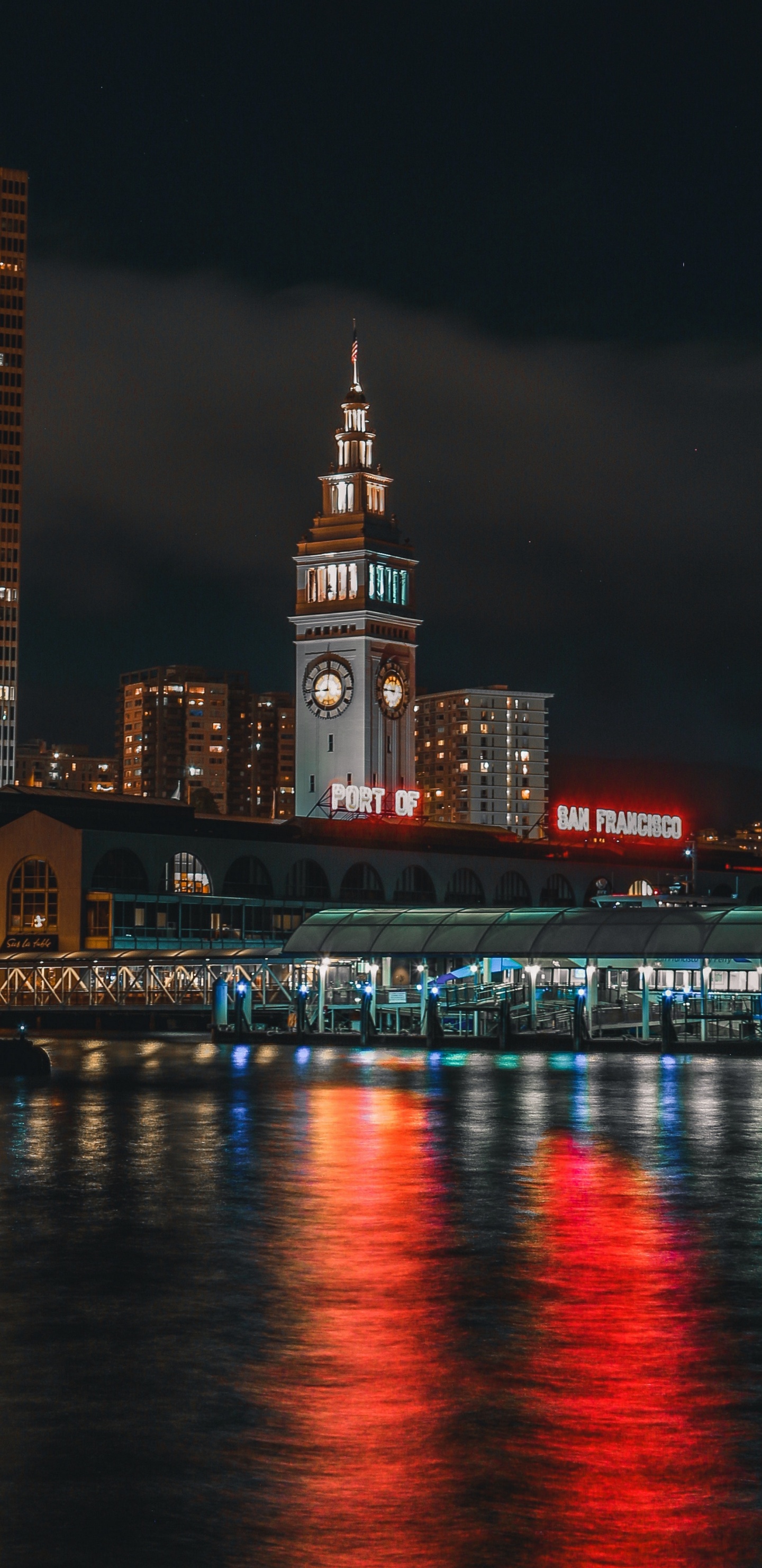 Bâtiments de la Ville Éclairés Près D'un Plan D'eau Pendant la Nuit. Wallpaper in 1440x2960 Resolution