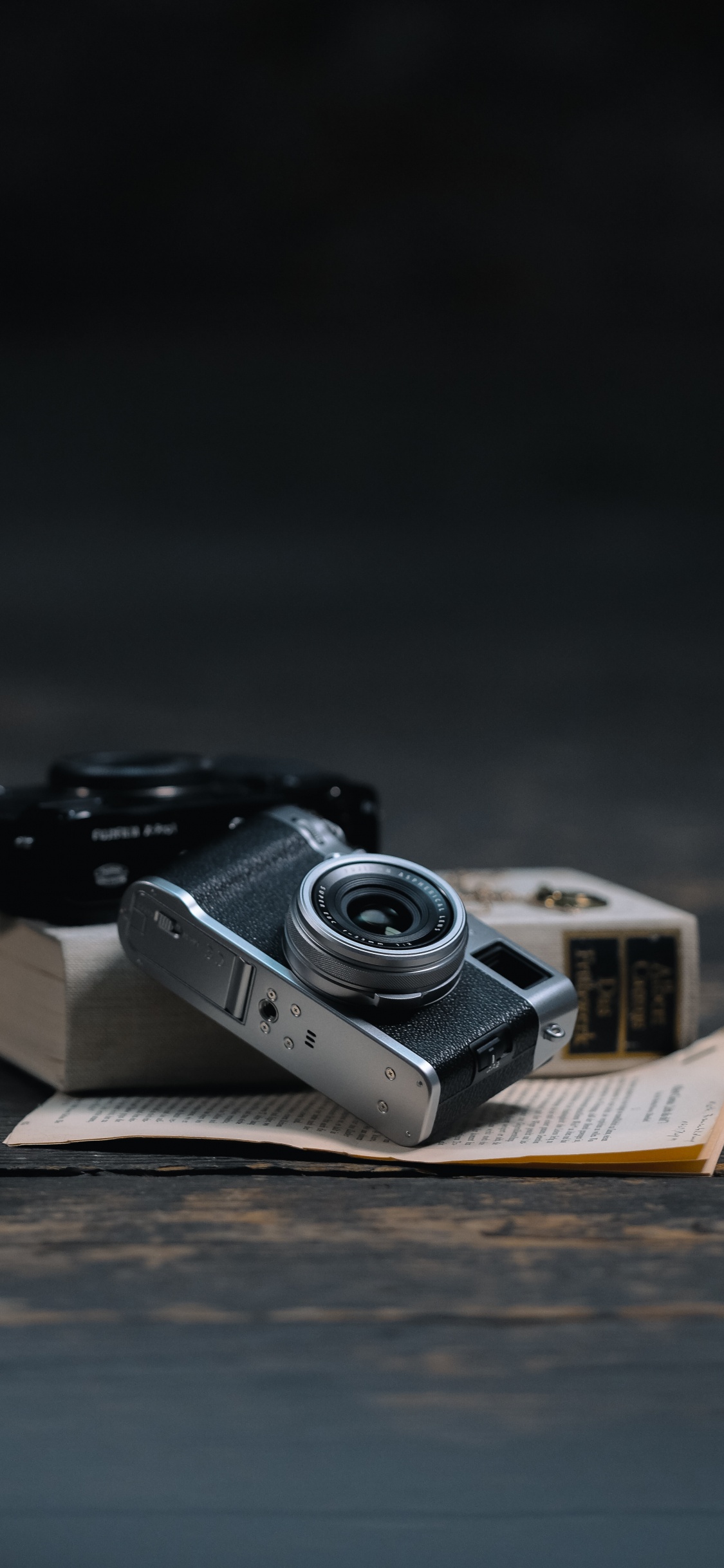 Appareil Photo Noir et Argent Sur Livre Marron. Wallpaper in 1125x2436 Resolution