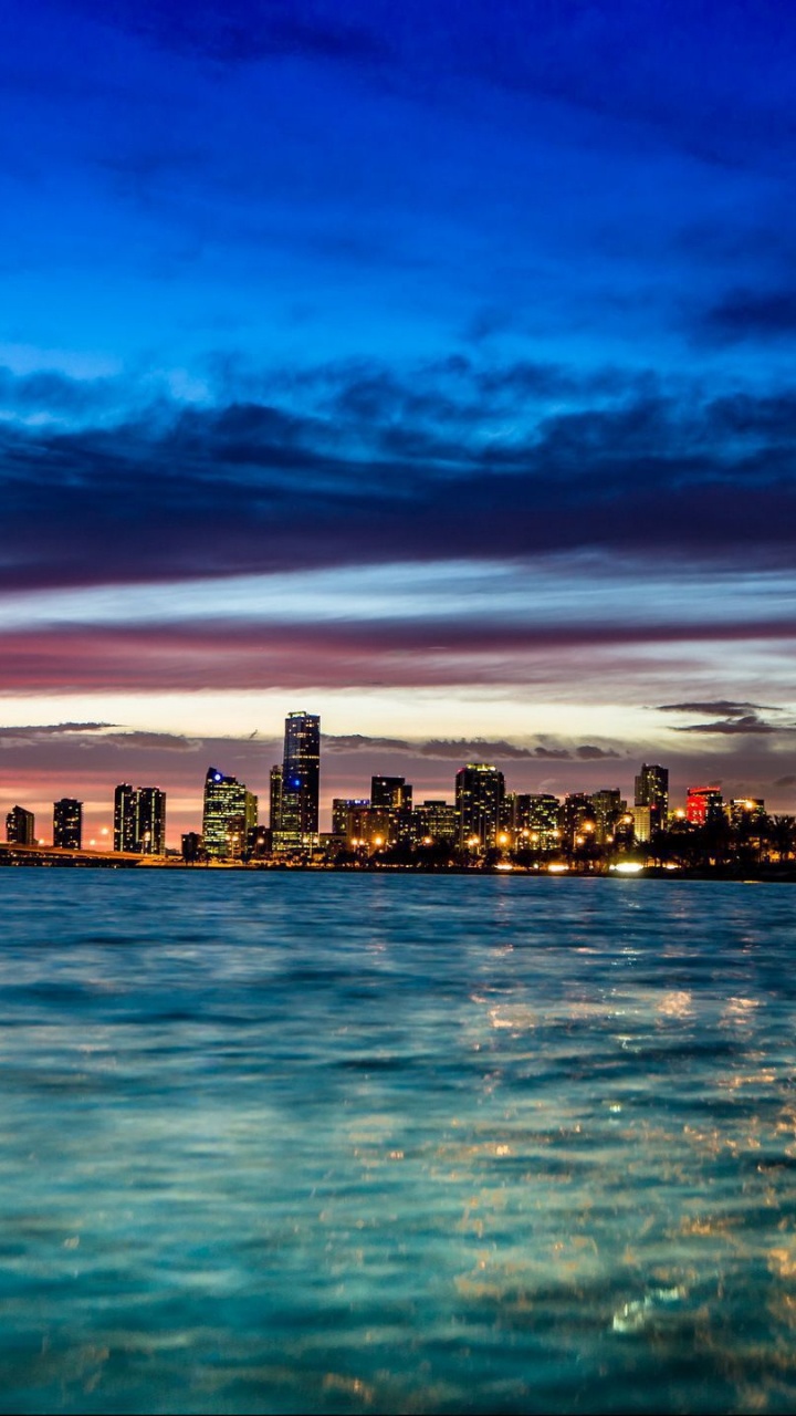 City Skyline Across Body of Water During Night Time. Wallpaper in 720x1280 Resolution