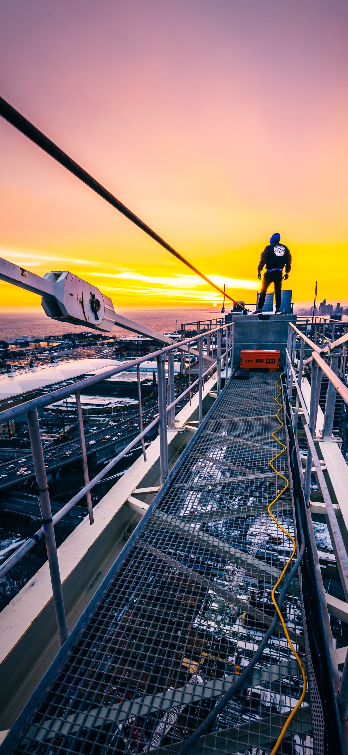 Homme en Veste Noire et Pantalon Noir Debout au Sommet du Bâtiment Pendant le Coucher du Soleil. Wallpaper in 1125x2436 Resolution