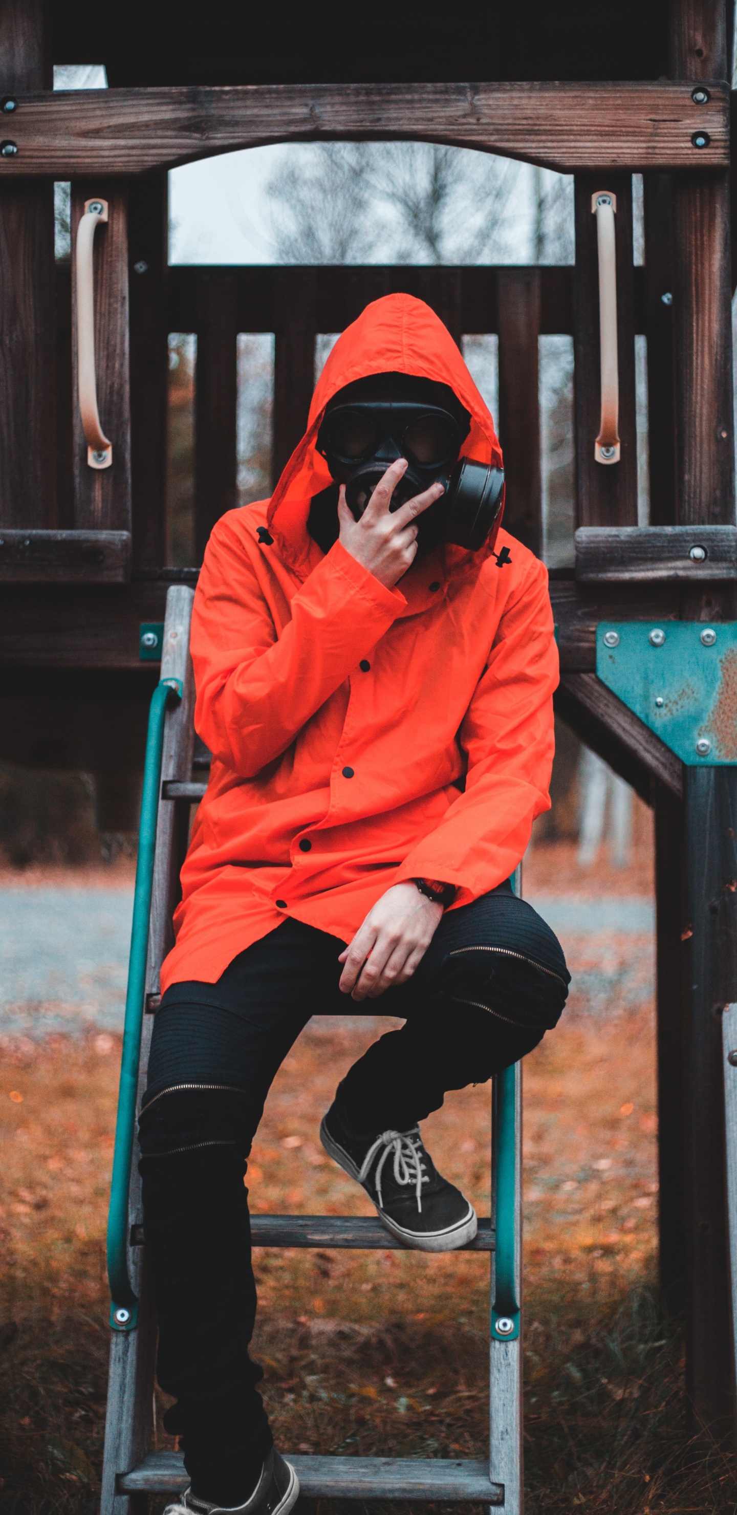 Frau in Orangefarbenem Hoodie Und Schwarzer Hose Sitzt Auf Braunem Holzzaun. Wallpaper in 1440x2960 Resolution