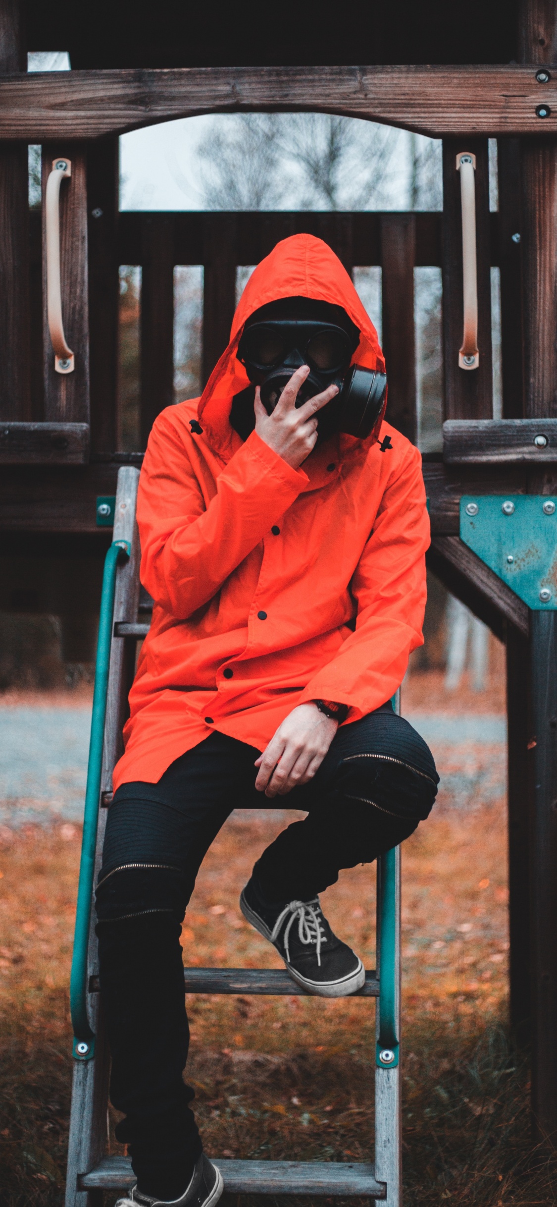 Femme en Sweat à Capuche Orange et Pantalon Noir Assis Sur Une Clôture en Bois Marron. Wallpaper in 1125x2436 Resolution