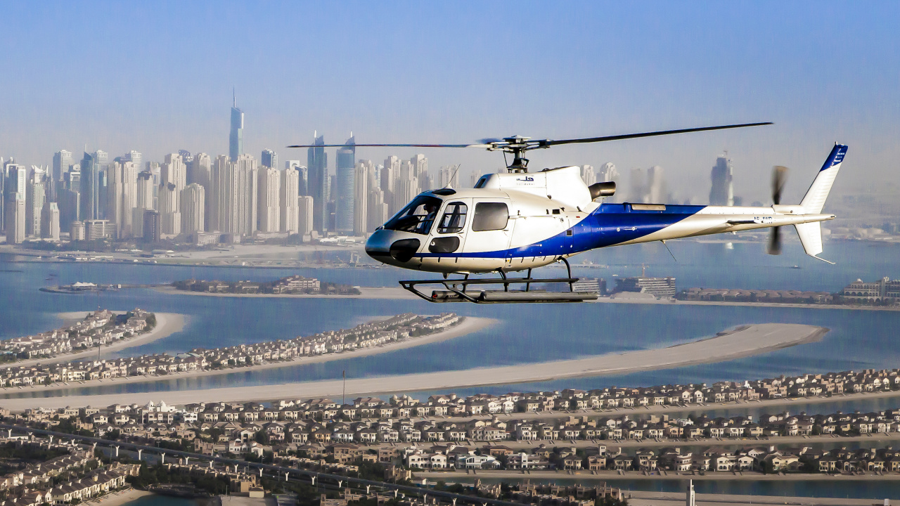 White and Blue Helicopter Flying Over City Buildings During Daytime. Wallpaper in 1280x720 Resolution