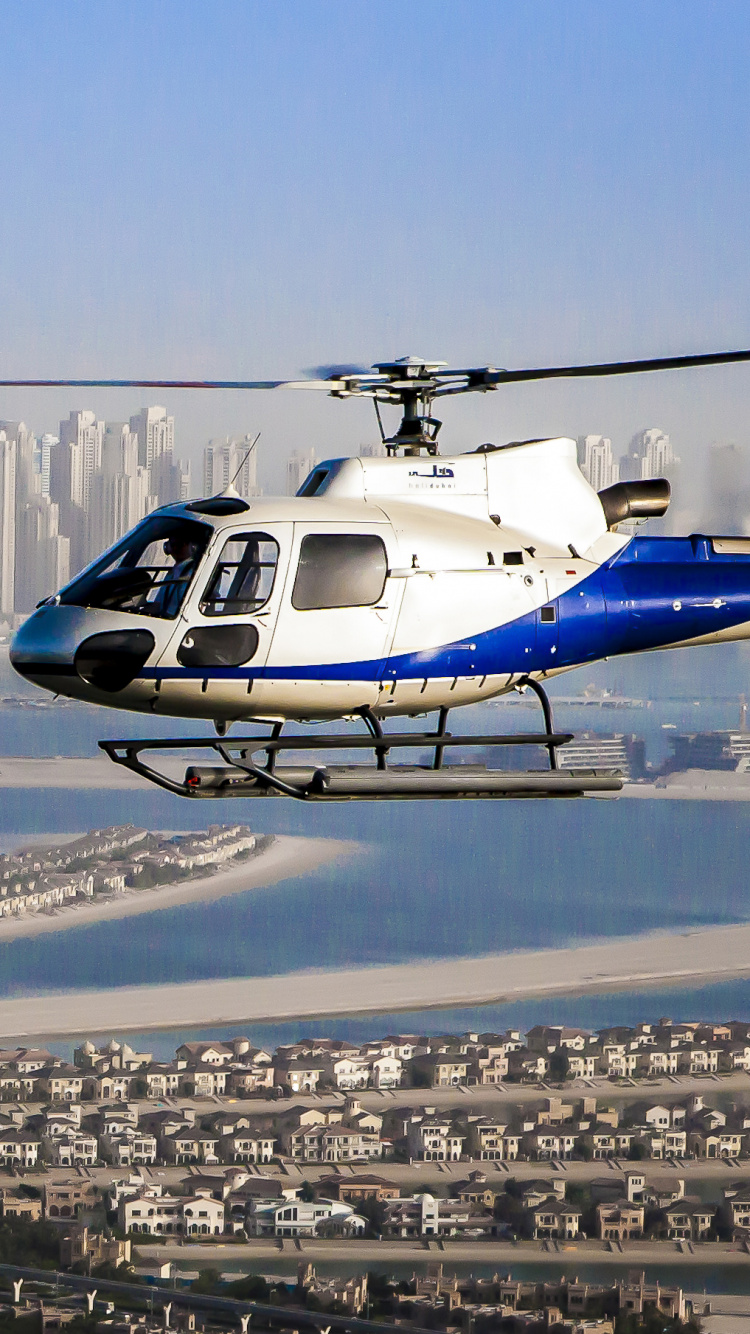 Helicóptero Blanco y Azul Sobrevolando Los Edificios de la Ciudad Durante el Día. Wallpaper in 750x1334 Resolution