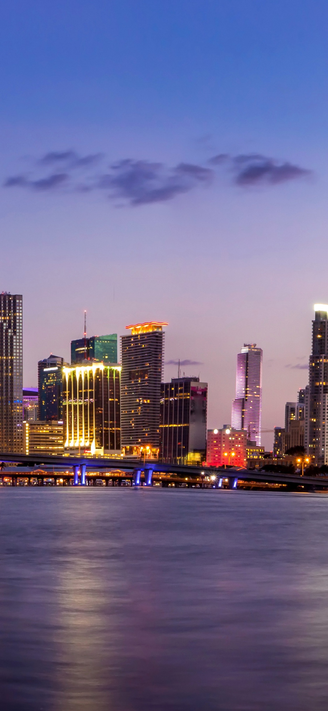 City Skyline Across Body of Water During Night Time. Wallpaper in 1125x2436 Resolution
