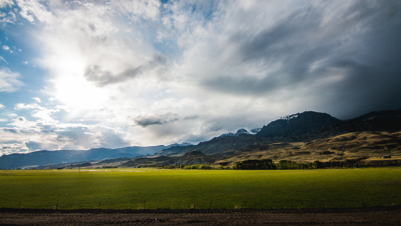 Green Grass Field Near Brown Mountain Under White Clouds and Blue Sky During Daytime. Wallpaper in 1280x720 Resolution